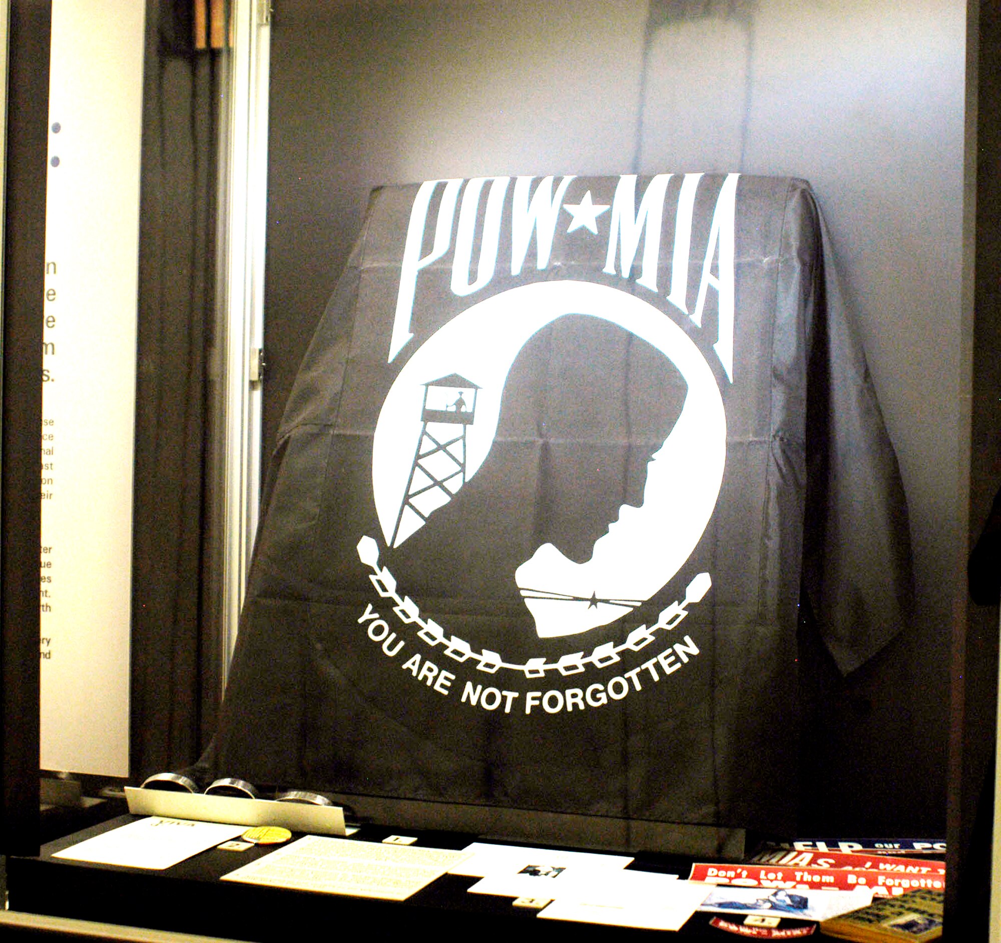 Articles in this display include a pre-addressed postcard to Ton Duc Thang, the president of North Vietnam, to enlist his support in determining the fate of Lt. Larry Potts at the National Museum of the U.S. Air Force in Dayton, Ohio. Despite repeated appeals like this one, North Vietnam remained unsympathetic. The black flag is the official POW/MIA flag, which is flown six times a year at designated federal sites. It was designed in 1971 by Newt Heisley, a World War II pilot and advertising artist who never profited from the uncopyrighted design. (U.S. Air Force photo)