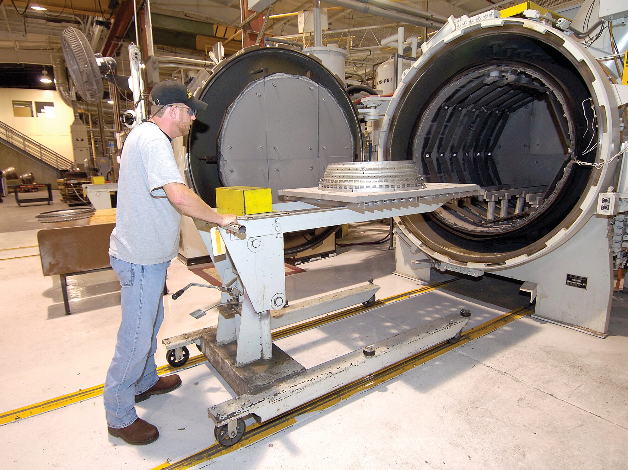 Wes Tison pushes an engine part into a vacuum furnace in the Heat Treatment Shop of Bldg. 3001. The simple act used to be a safety hazard with a slippery floor and floor rails that were tripping hazards. Through shop personnel suggestions, the trip hazards on the 18 furnaces were painted bright yellow and a new grip texture on the floor makes pushing the cart a safer act. (Air Force photo by Margo Wright) 
