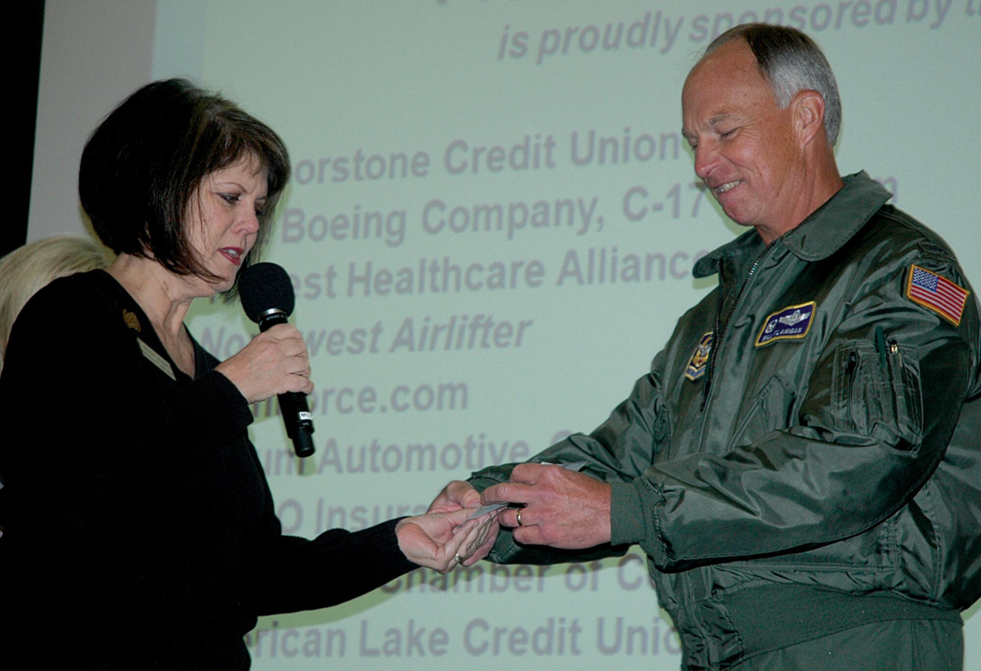 MCCHORD AIR FORCE BASE, Wash., Carlene Joseph of the Pierce Military Business Alliance in Lakewood, Wash.,  presents to Col. William Flanigan, 446th Airlift Wing commander, a $2,000 check for the wing's Care & Share program during a commander's call here Nov. 8. Care & Share supports Reserve Airmen in a variety of ways; from short-term loans to help pay rent to Thanksgiving and Christmas baskets for struggling families.  The generous gift from PMBA was matched by the Hawks Prairie Rotary Club, Lacey, Wash., which also donated $2,000 to Care & Share.  ?Our goal is to make sure the 446th Airlift Wing is taken care of every year,? said Ms. Joseph. Members of the PMBA raised the money by collecting donations outside local Top Food & Drug stores and organizing a golf tournament at Meadow Park Golf Course in September. (U.S. Air Force photo/Staff Sgt. Grant Saylor)