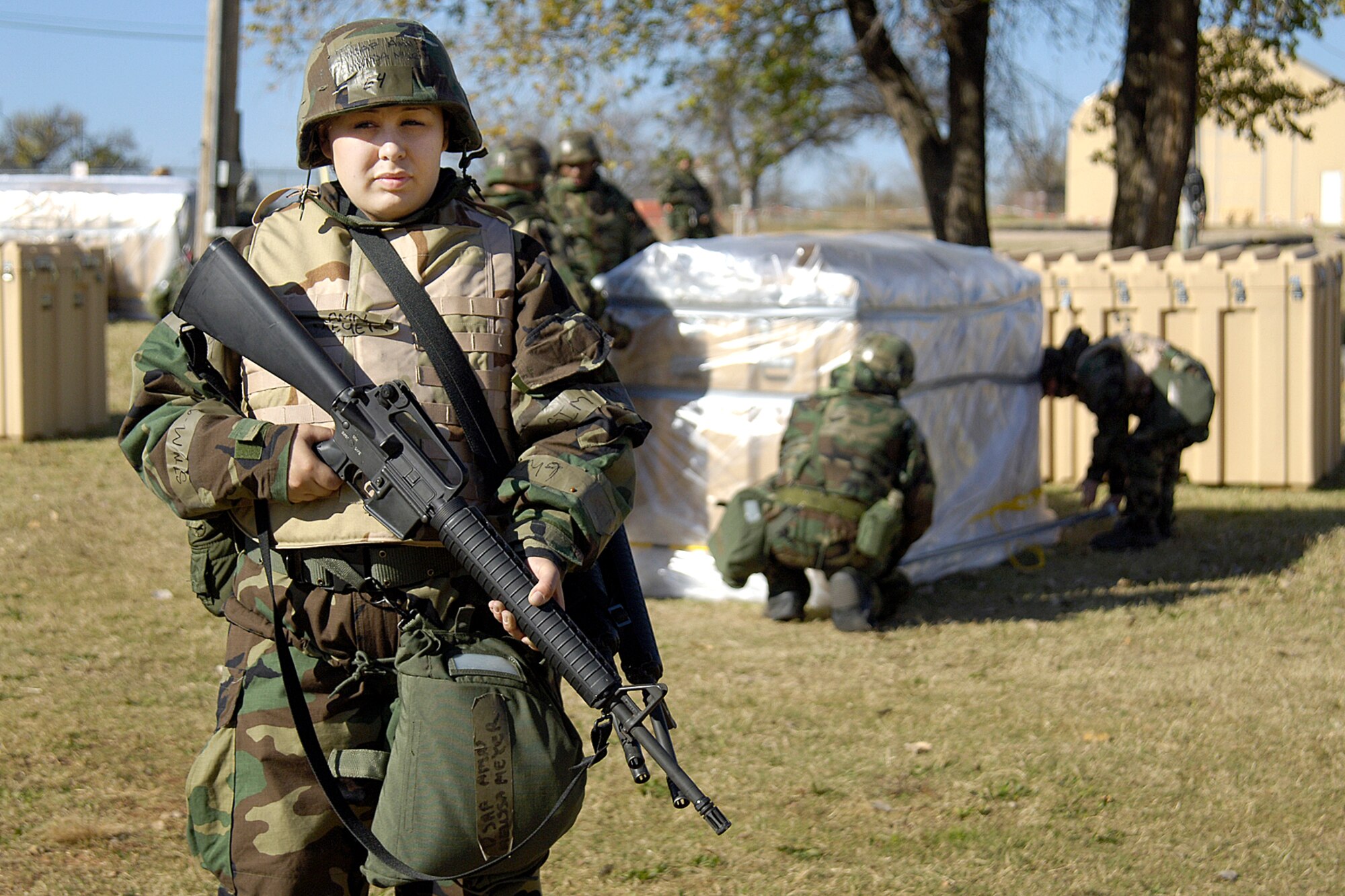 During an ORI exercise at Glenwood Training Area, Airman Melissa Meyer guards fellow Airmen who wrap assets in plastic to protect them from possible contaminant. Airman Meyer is with the 72nd Dental Squadron. (Air Force photo by Margo Wright)