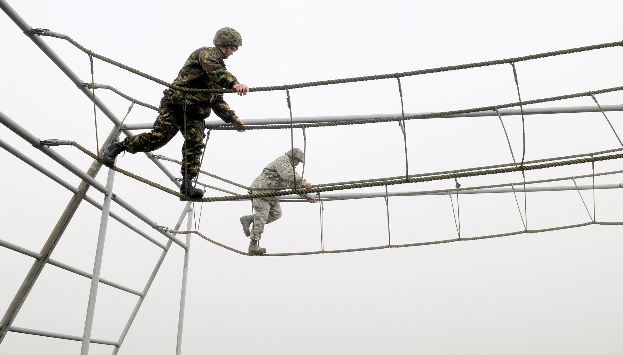 A British airman (left) and 1st Lt. Xzavior Hill, traverse a rope bridge as part of the Ultimate Challenge 2 activity of Leadership, Ethos and Air Power Day at Royal Air Force Marham Nov. 9, 2009. About 40 Airmen from RAFs Mildenhall and Lakenheath participated in the leadership building opportunities with their British counterparts. The event is normally hosted three times a year for RAF troops. The overall goal is to foster teambuilding and teach effective leadership techniques. Lieutenant Hill is from the 100th Civil Engineer Squadron. (U.S. Air Force photo/Senior Airman Thomas Trower)
