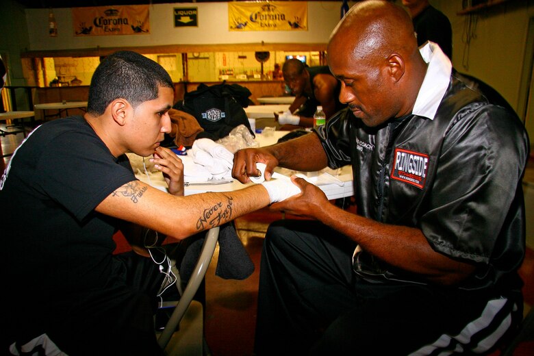 Tinker head coach Lavell Sims, right, tapes the hands of boxer Jose Robles several minutes before his fight Nov. 7 in Tulsa. Sims was pleased with his fighters’ performance Saturday, but will be pushing his boxers to the limit in preparing for their home bout Nov. 20 at the Gerrity Fitness and Sports Center. (Air Force photo by John Stuart) 