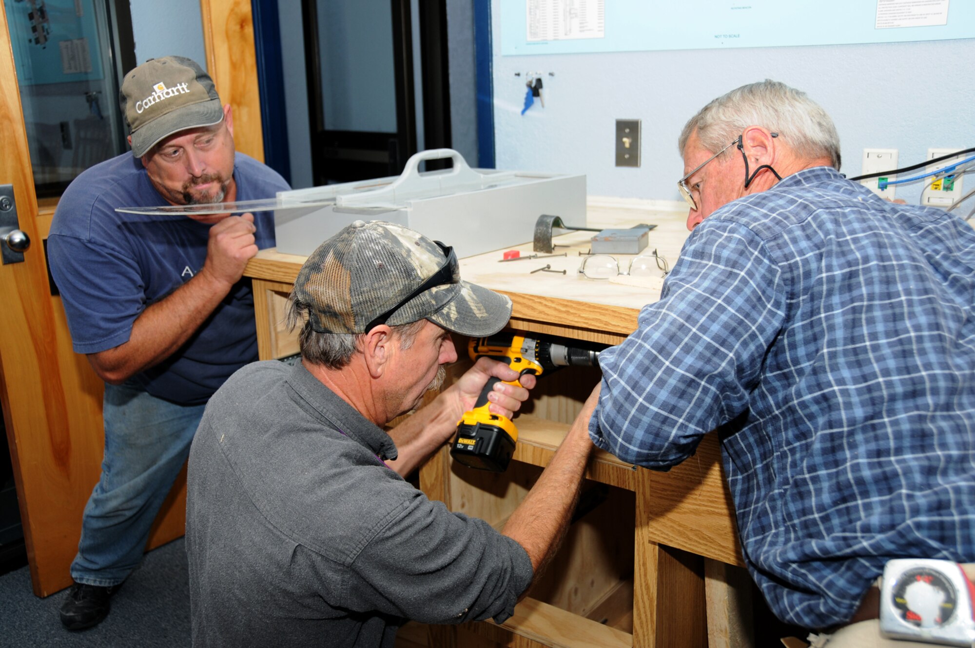 From left, woodcrafters Greg Wilson, Bobby Cannette and Art Fountain install the new work station at base operations Nov. 2.   (U.S. Air Force photo by Kemberly Groue)