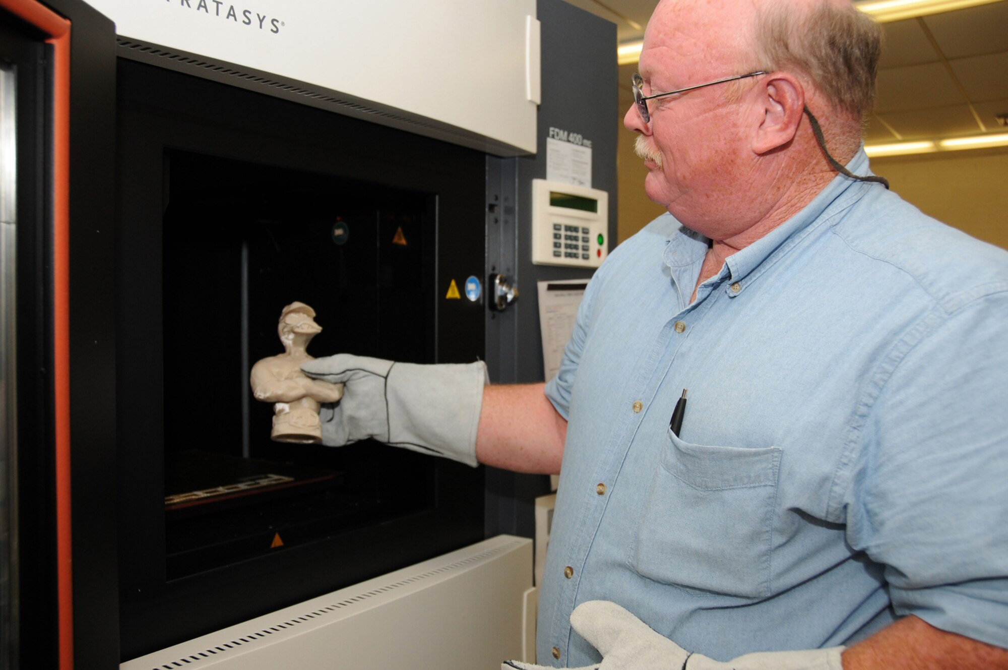 Tom Capers takes out a model from the fused deposition modeling machine now located at trainer development.  (U.S. Air Force photo by Kemberly Groue)