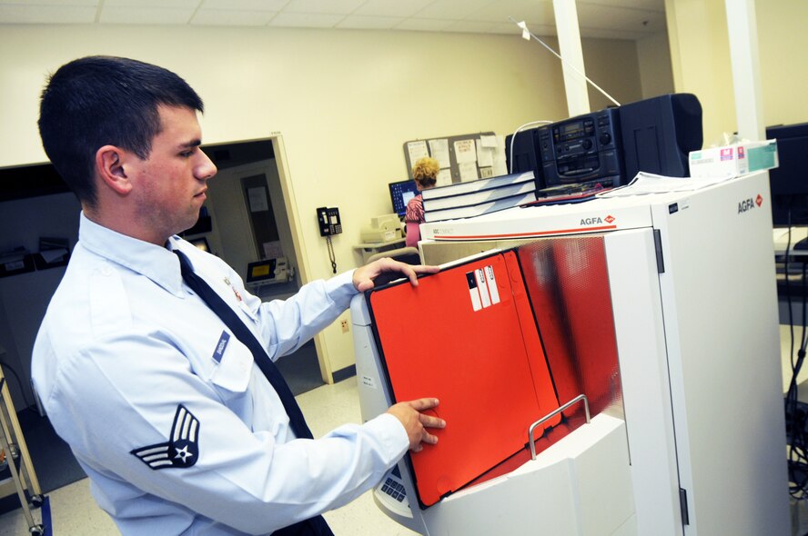 Senior Airman Vincente Sandoval inserts imaging plates into a multiloader processor. 