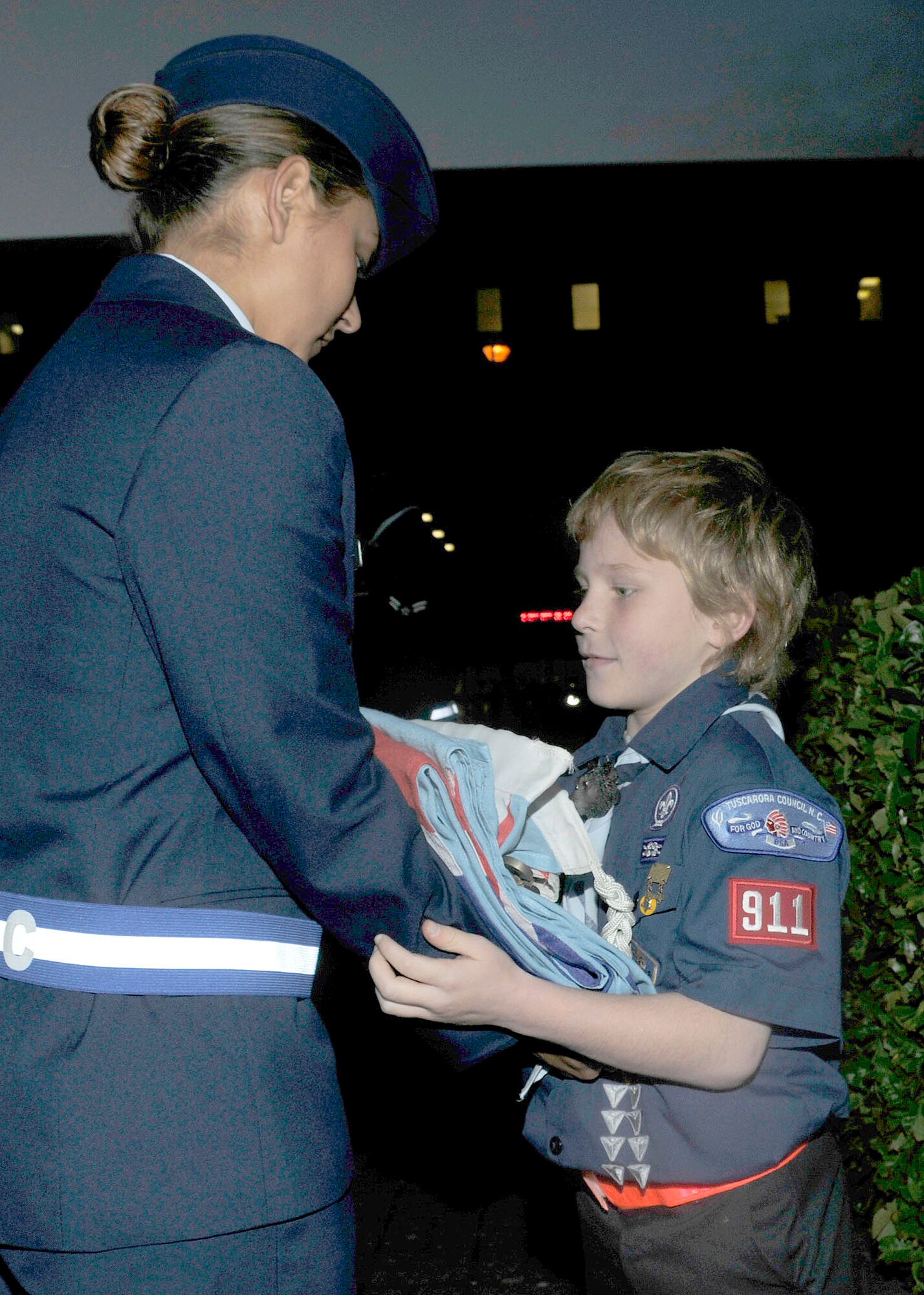 Zachary Moenter, cub scout, son of Jennifer and Master Sgt. Jason Moenter, 48th Aircraft Maintenance Squadron weapons maintenance NCO in charge, receives the British flag from Airman Jacklynn Stanford, First Term Airmen Center student, during a retreat ceremony at RAF Lakenheath, England, Nov. 9. The Cub Scouts chose a retreat ceremony for their community service project.  (U.S. Air Force photo/Airman 1st Class Eboni Knox)