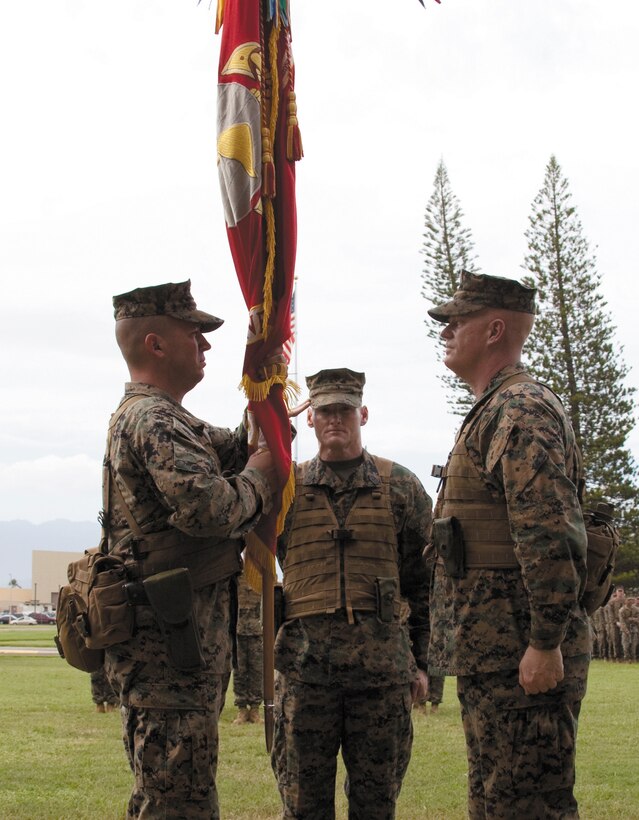 Col. James Bierman (left) receives the colors and assumes command of 3rd Marine Regiment from Col. Duffy White (right) during a change of command ceremony while Sgt. Maj. Paul McKenna, regimental sergeant major, salutes the exchange.