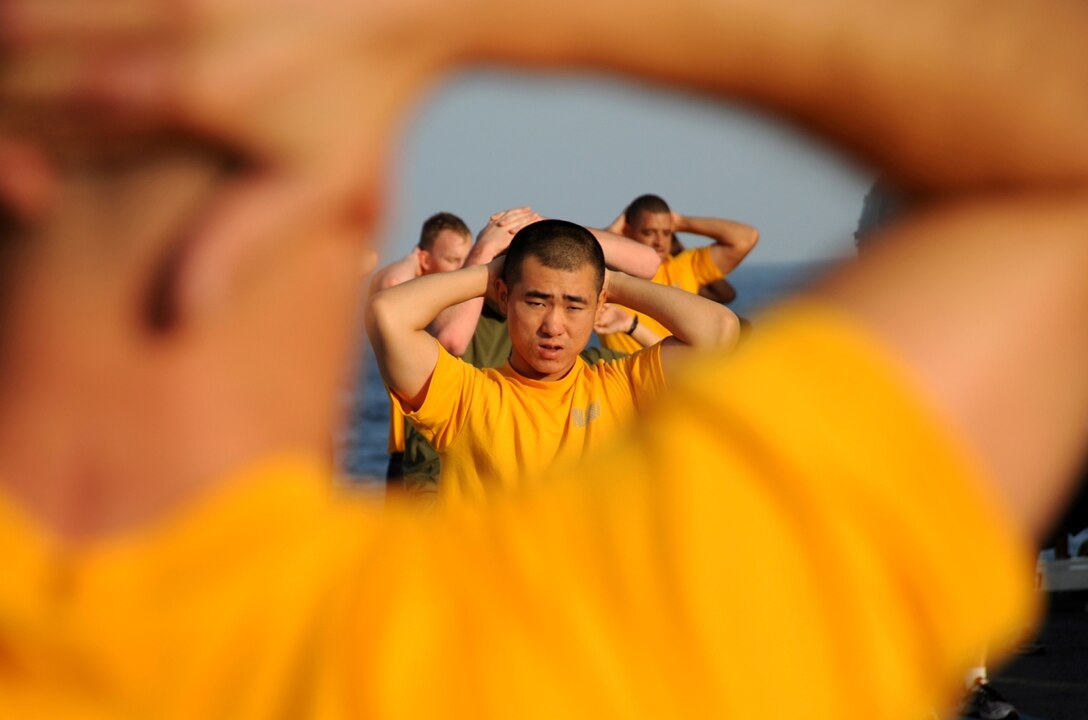 Seaman Jong Oh, an aviation support equipment technician, exercises on the flight deck of USS Bonhomme Richard during a morning physical training session Nov. 12. The amphibious ship is conducting maritime security operations in the 5th Fleet area of operations.