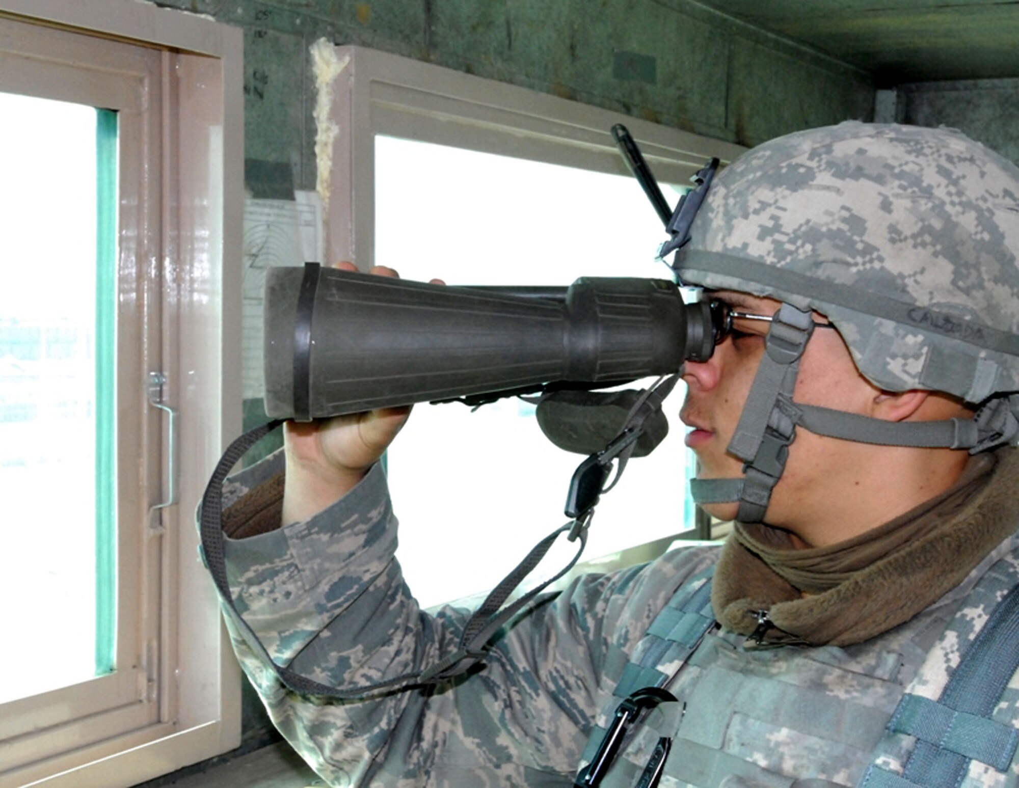 BAGRAM AIRFIELD, Afghanistan -- Airman Aaron Calzada with the 455th Expeditionary Security Forces Squadron watches a group of locals near the perimeter at an entry control point here. Airman Calzada, a Lancaster, Calif., native, is deployed from the 49th Security Forces Squadron based in Holloman Air Force Base, N.M., and works jointly with Task Force Cyclone, his security forces team, Afghan security guards and others to secure BAF day and night. (U.S. Army photo/Spc. William E. Henry)