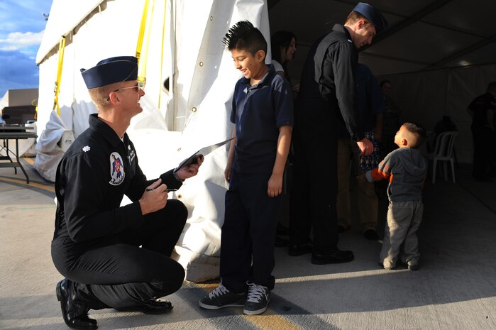 NELLIS AIR FORCE BASE, Nev.--  Angel Sotelo, a seven year-old diagnosed with fanconi anemia gets his booklet autographed by Lt. Col. Derek Routt, U.S. Air Force Aerial Demonstration Team Thunderbirds operations officer, during the rehearsal show for the Nellis Open House Nov. 13. Angel was invited to attend the rehearsal day for the open house through the Make a Wish Foundation. The Make a Wish Foundation is a non-profit organization aimed toward granting wishes of children with life-threatening conditions. (U.S. Air Force photo by Tech. Sgt. Michael R. Holzworth)