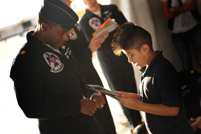 NELLIS AIR FORCE BASE, Nev.-- Angel Sotelo, a seven year-old diagnosed with fanconi anemia gets his booklet autographed by Maj. Tyrone Douglas, U.S. Air Force Aerial Demonstration Team Thunderbirds lead solo pilot, during the rehearsal show for the Nellis Open House Nov. 13. Angel was invited to attend the rehearsal day for the open house through the Make a Wish Foundation. The Make a Wish Foundation is a non-profit organization aimed toward granting wishes of children with life-threatening conditions. (U.S. Air Force photo by Tech. Sgt. Michael R. Holzworth)