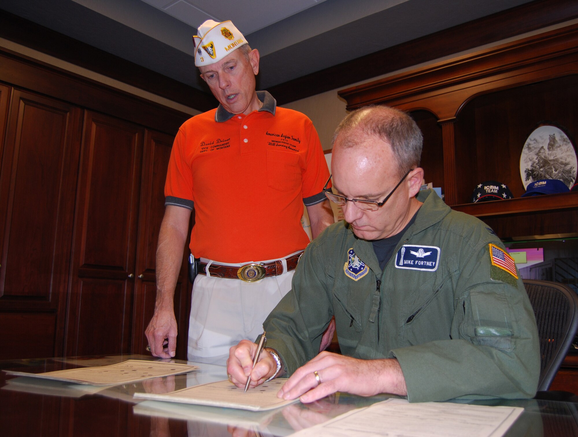 American Legion representative David Driver waits as Col. Michael Fortney, 341st Missile Wing commander, reads and signs the Montana Community Covenant. The covenant is a document that pledges support for the armend forces, recognizing their sacrifices and commitment in support of our nation's security. It was signed by Montana representatives for all branches of the service as well as the governor, and representatives of the Montana Veteran Service Organizations. (U.S. Air Force photo/Tech. Sgt. Marcus McDonald)