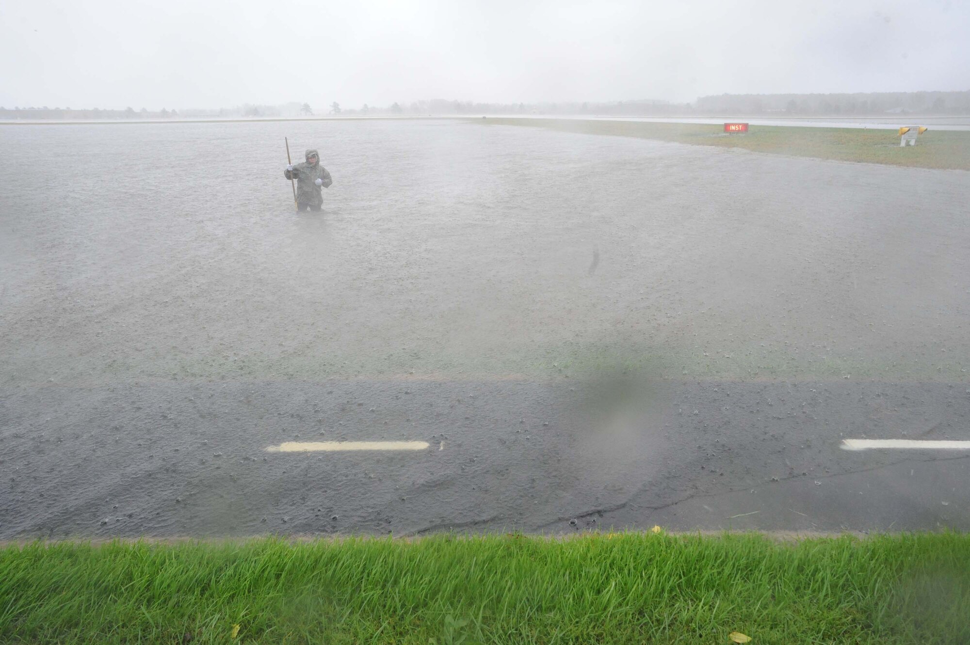 LANGLEY AIR FORCE BASE, Va. – Airman 1st Class Jason Brown measures the water's depth near the flightline Nov. 12.  A nor'easter dropped 8-10 inches of rain on Langley over the course of three days with wind gusts up to 55 mph.  (U.S. Air Force photo/Staff Sgt. Barry Loo)