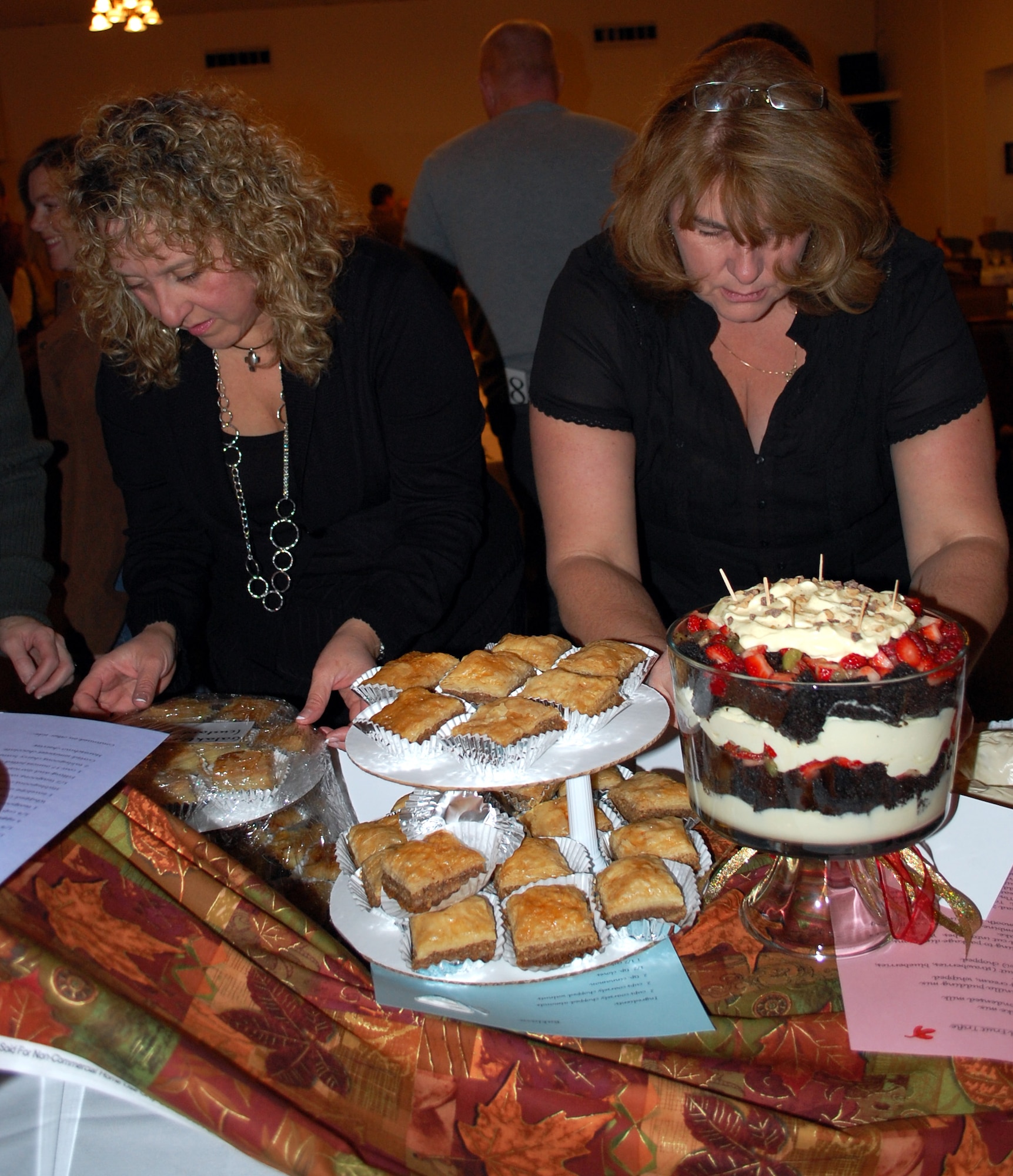 Kim Buzzell, right) helps Jackie Pappas unwrap the two Greek desserts she prepared for the dessert auction. She made well-know Greek dessert baklava and a not-so-well-known Greek custard filled dessert call Galaktoboureko. (U.S. Air Force photo/Valerie Mullett)