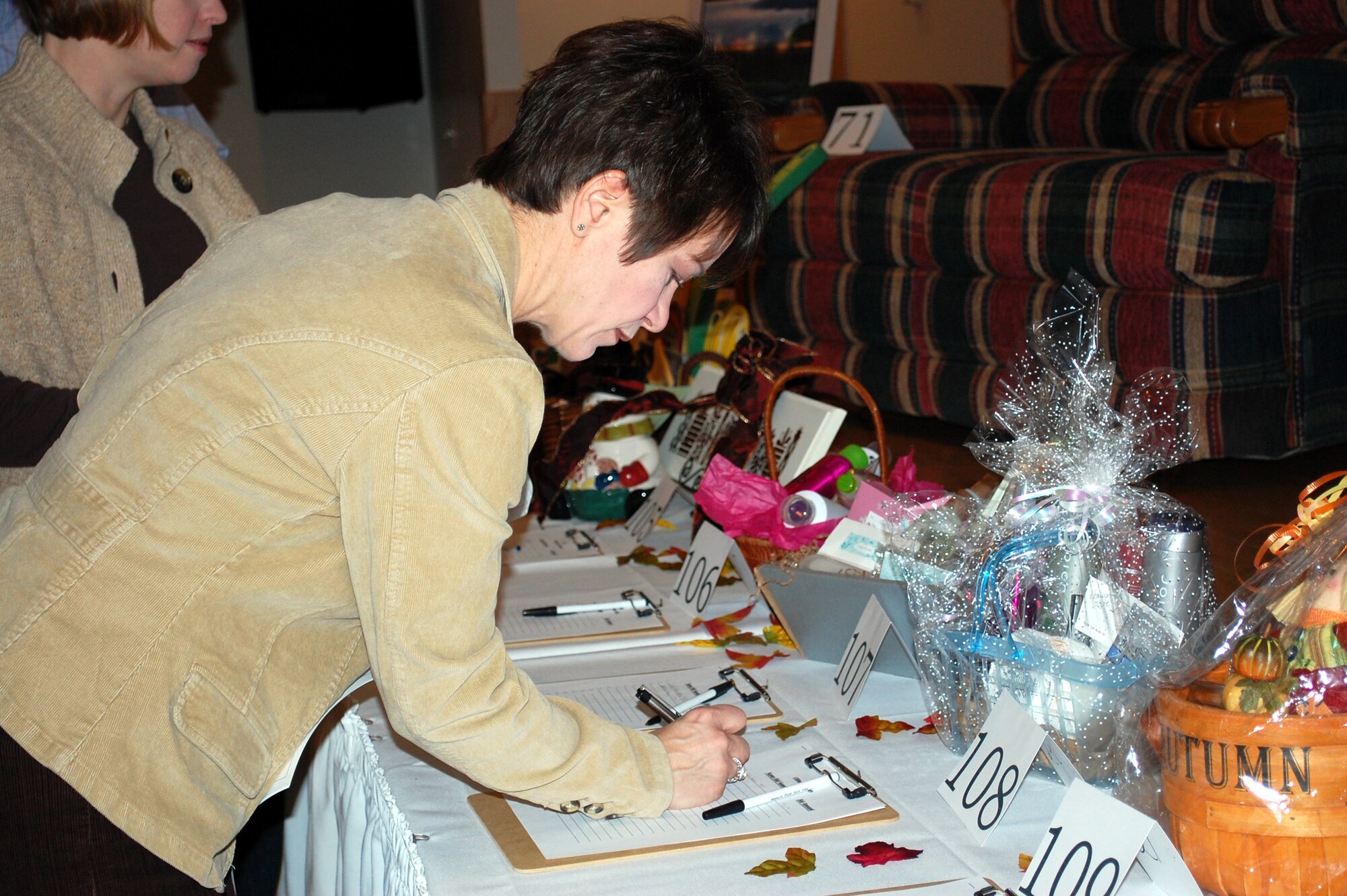 Diane Lair makes a silent auction bid on a basket of beauty products donated by Le Salon at the 21st annual Mercantile Auction Nov. 7 at the Grizzly Bend Club. (U.S. Air Force photo/Valerie Mullett)