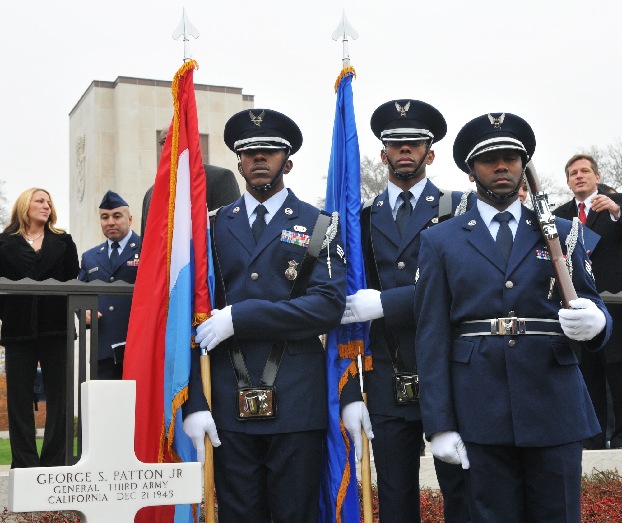 SPANGDAHLEM AIR BASE, Germany -- From left to right, Senior Airmen Jason Myers, Brandon Jackson, and Jerrime Williams, 702nd Munitions Support Squadron Color Guard members, stand at attention in front of the gravestone of Gen. George S. Patton Jr., Third Army commander during World War II, during the annual Veterans Day ceremony at the Luxembourg American Cemetery and Memorial in Luxembourg City Nov. 11. The 50.5 acre cemetery, which is one of 14 American cemeteries established overseas after World War II, contains the remains of more than 5,000 American servicemembers who died fighting in World War II. (U.S. Air Force photo/Maj. Jillian Torango)