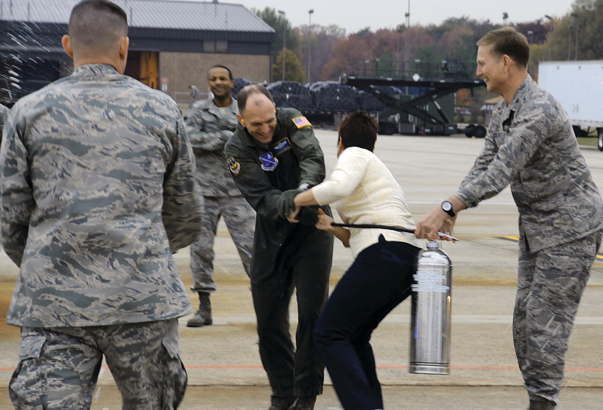 Maj. gen. Ralph Jodice, Air Force District of Washington commander wrestles with his wife, Judy, over a fire extinguisher she and Col. Phillip Gibbons, AFDW vice commander, were using to try to douse him with after his final flight Tuesday at Joint base Andrews-NAF Washington, Md. 
General Jodice was welcomed back to Andrews by base leaders after flying over the Pentagon and in Capitol airspace, with a tradition that dates back to the vietnam war era, when pilots who completed 100 safe combat missions were doused down with fire hoses upon landing. On Wednesday, General Jodice is slated to pass the AFDW guidon to Maj. Gen. Darrell Jones during a change of command ceremony in Hagnar 3 at Andrews.