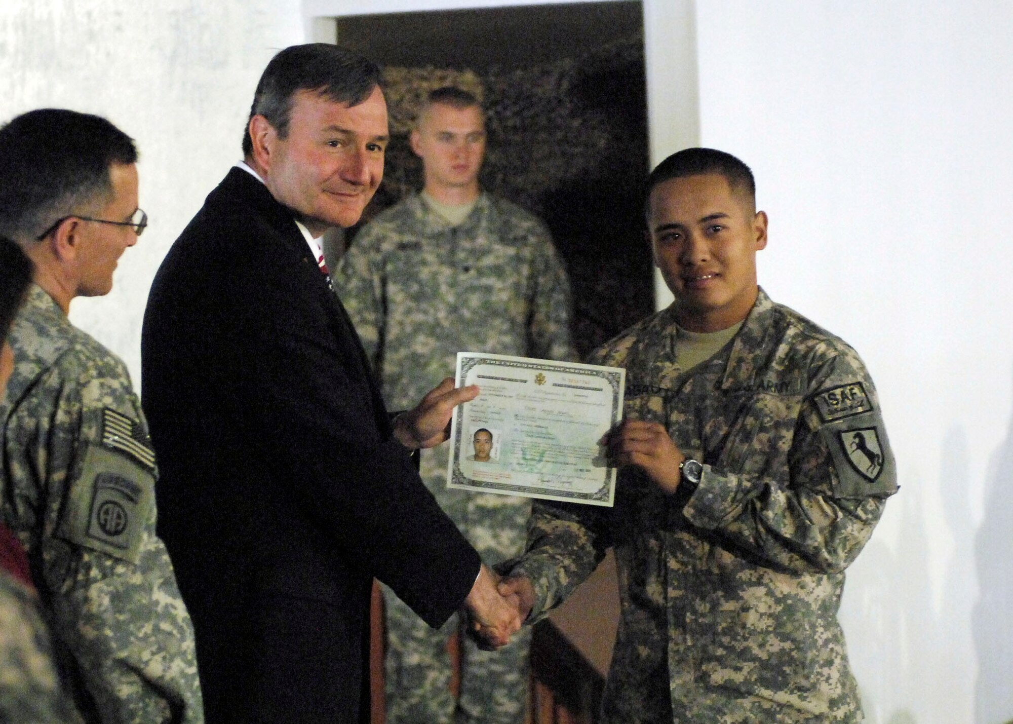 BAGRAM AIRFIELD, Afghanistan -- Mr. Karl Eikenberry, U.S. Ambassador to Afghanistan, presents a certificate of naturalization to Army Cpl. Cylee Yagao, a Security Forces team leader for the Khost Provincial Reconstruction Team, Nov. 12, 2009.  A Naturalization Ceremony was held at the morale, welfare and recreation clamshell here making more than 130 military members U.S. citizens.   Corporal Yagao, a Philippine native, found out that he was part of the Bagram naturalization ceremony through emails and phone calls from his Las Vegas home station, 1-221st Calvary Regiment.  (U.S. Air Force photo/Senior Airman Felicia Juenke)