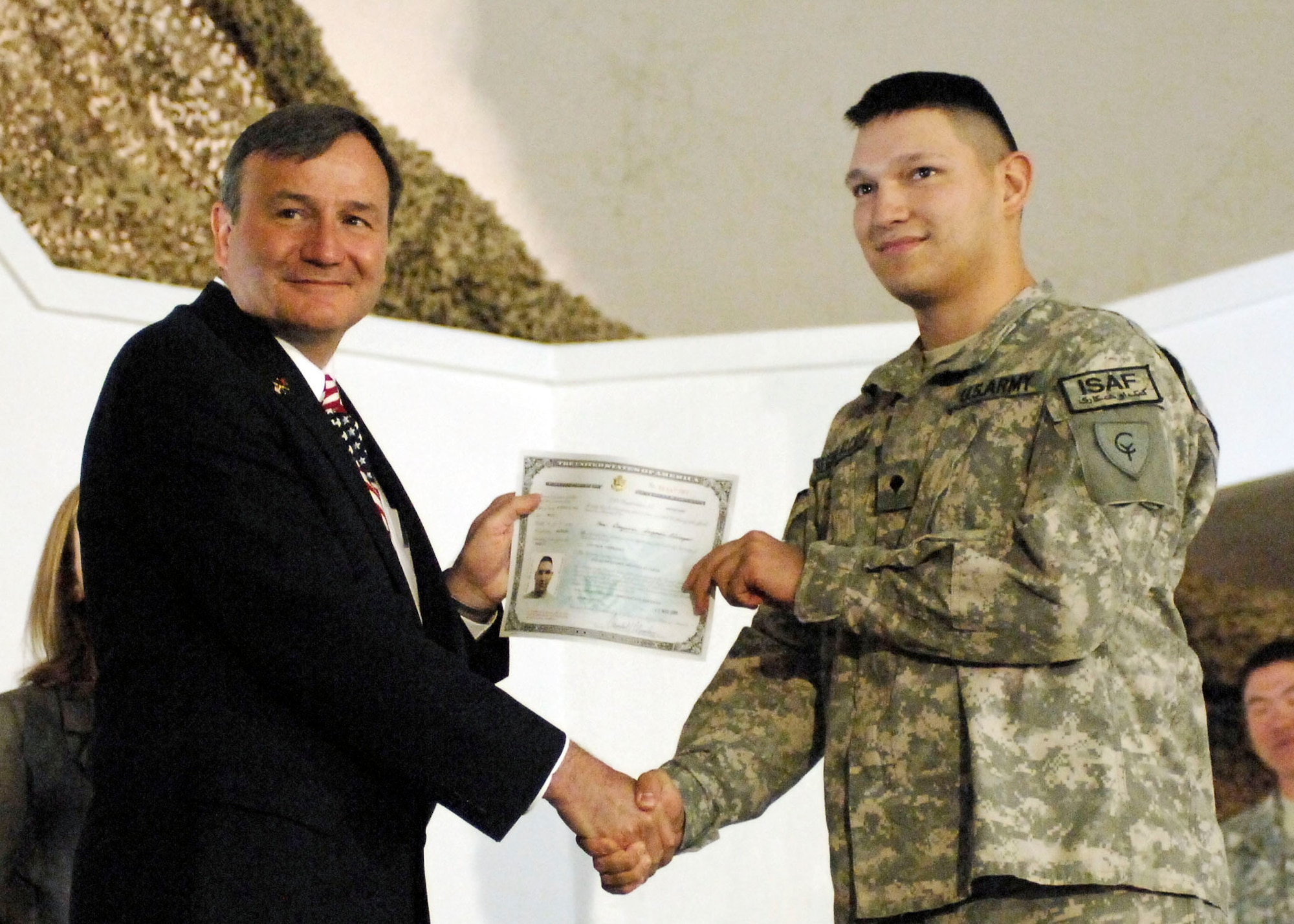 BAGRAM AIRFIELD, Afghanistan -- Mr. Karl Eikenberry, U.S. Ambassador to Afghanistan, presents a certificate of naturalization to Army Spc. Oscar Segovia-Alcazar, the mandatory training non-commissioned officer in charge from Task Force Cyclone, Nov. 12, 2009.  A Naturalization Ceremony was held at the morale, welfare and recreation clamshell here making more than 130 military members U.S. citizens.  Specialist Segovia-Alcazar is deployed from the Indiana Air National Guard and hails from Indianapolis.  (U.S. Air Force photo/Senior Airman Felicia Juenke)