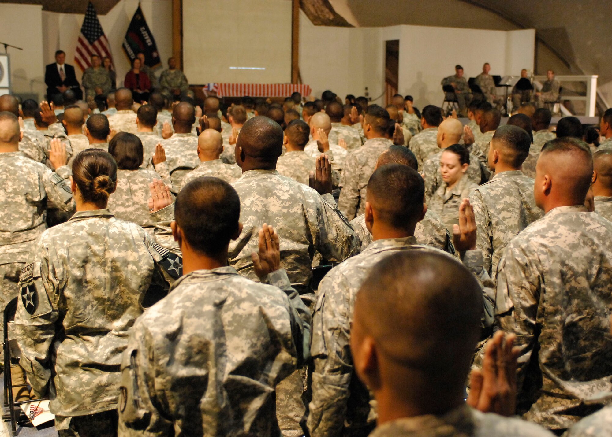 BAGRAM AIRFIELD, Afghanistan -- Mr. Robert Looney, district director of U.S. Citizenship and Immigration Services, Bangkok District, leads military members in taking the Oath of Allegiance Nov. 12, 2009.  A Naturalization Ceremony was held at the morale, welfare and recreation clamshell here making more than 130 service men and women U.S. citizens.  A video message was played from President Barack Obama, congratulating and thanking them for their continued service.  (U.S. Air Force photo/Senior Airman Felicia Juenke)