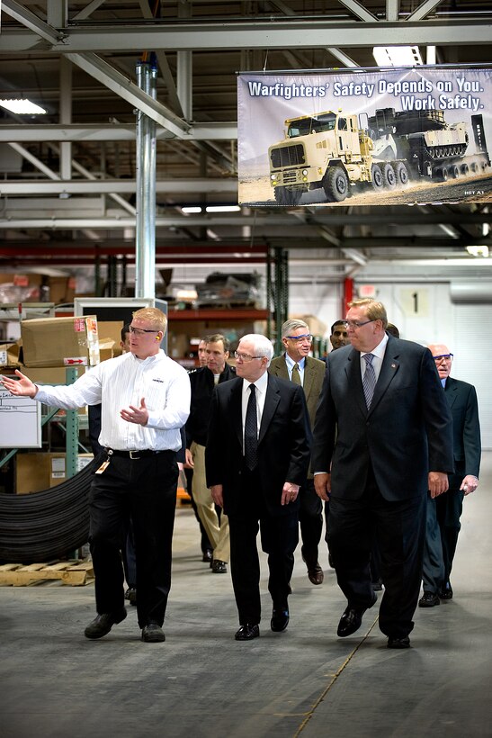 Jake Jones, left, operations manager, and Robert Bohn, right, chairman and CEO of Oshkosh Corp., give Defense Secretary Robert M. Gates a tour of the M-ATV production facility in Oshkosh, Wis., Nov. 12, 2009.