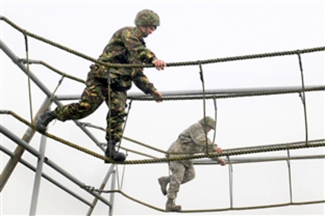 A British airman, left, and  U.S. Air Force 1st Lt. Xzavior Hill traverse a rope bridge as part of the Ultimate Challenge 2 activity of Leadership, Ethos and Air Power Day on Royal Air Force Marham, Nov. 9, 2009. About 40 U.S. airmen participated in the leadership building opportunities with their British counterparts. Hill is assigned to the 100th Civil Engineer Squadron.