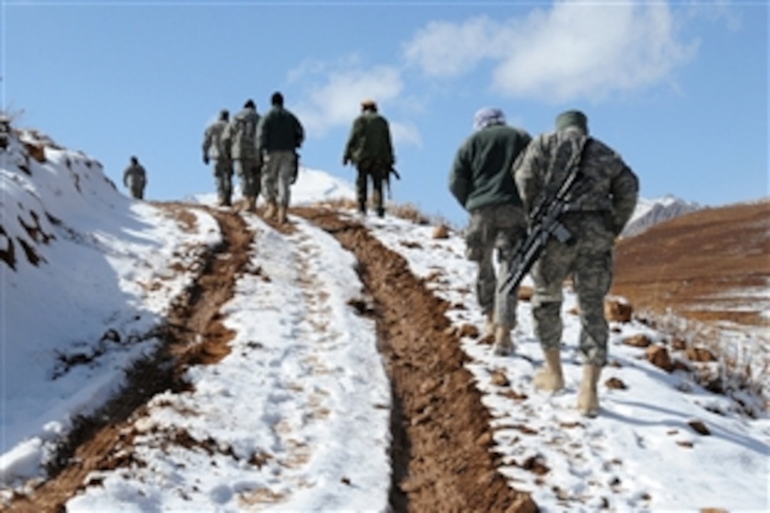 Members of Provincial Reconstruction Team Ghazni and Afghan national police walk up a snowy hill after their vehicles became stuck in the mud in the Nawur district, Ghazni province, Afghanistan, Nov. 8, 2009. The team's members visited the district to perform quality assurance control on a collapsed karza and two comprehenisve health clinics.