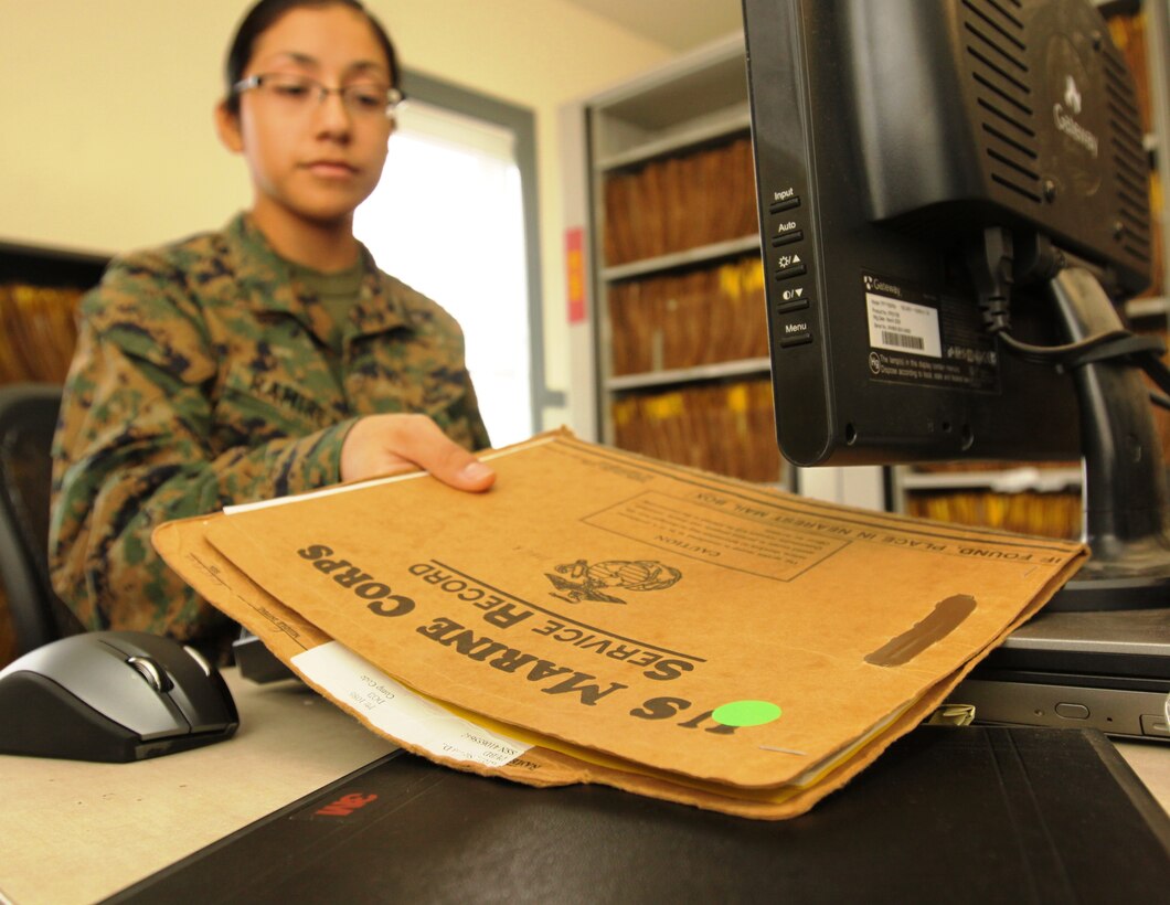 Lance Cpl. Saira J. Ramirez, personnel clerk, Installation Personnel Administration Center, Marine Corps Base Camp Pendleton, electronically scans a Service Record Book over the newly implemented electronic tracking pads, Nov. 13.
