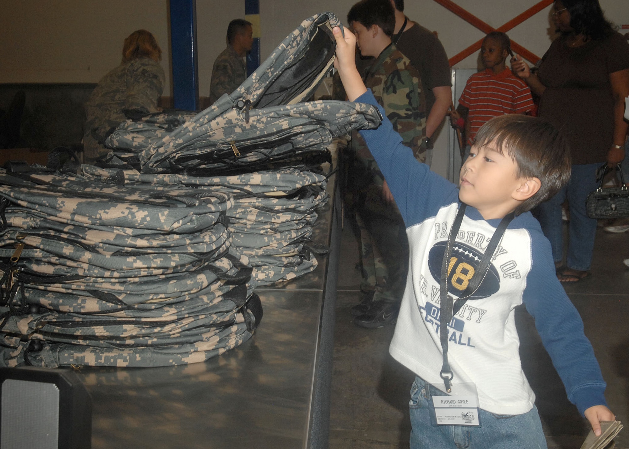 Richard Coyle, 6, son of Chief Master Sgt. Richard Coyle, 355th Medical Group superintendent, is issued a back pack while processing through the uniform and mobility bag lines here, Nov. 7. Representatives from various Tucson organizations joined with volunteers from base squadrons and other services to support the Junior Expeditionary Forces event. The volunteers set up face painting, entomology exhibits, an obstacle course and various arts and craft stations for the kids to enjoy. (U.S. Air Force photo/Airman
Jerilyn Quintanilla)
