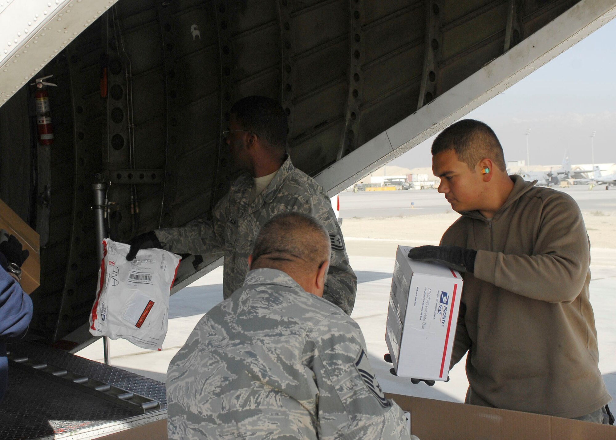BAGRAM AIRFIELD, Afghanistan -- Airman 1st Class Jericks Silver (right), Master Sgt. Roque Fuentes (middle) and Tech. Sgt. Johnnie Macklin (left) work as a team to load mail onto an aircraft Nov. 15, 2009.  All the Airmen are air transportation members from the short take off and landing office of the 455th Expeditionary Aerial Port Squadron.  The STOL office is in charge of delivering personnel and mail to different forward operating bases.   Airman Silver is deployed from Travis Air Force Base, Calif., and hails from Hamilton, Mo.  Sergeant Fuentes is deployed from Lackland AFB, Texas and hails from Corpus Christi, Texas. Sergeant Macklin, a native of Atlanta, is deployed from Keesler AFB, Miss.  (U.S. Air Force photo/Senior Airman Felicia Juenke)