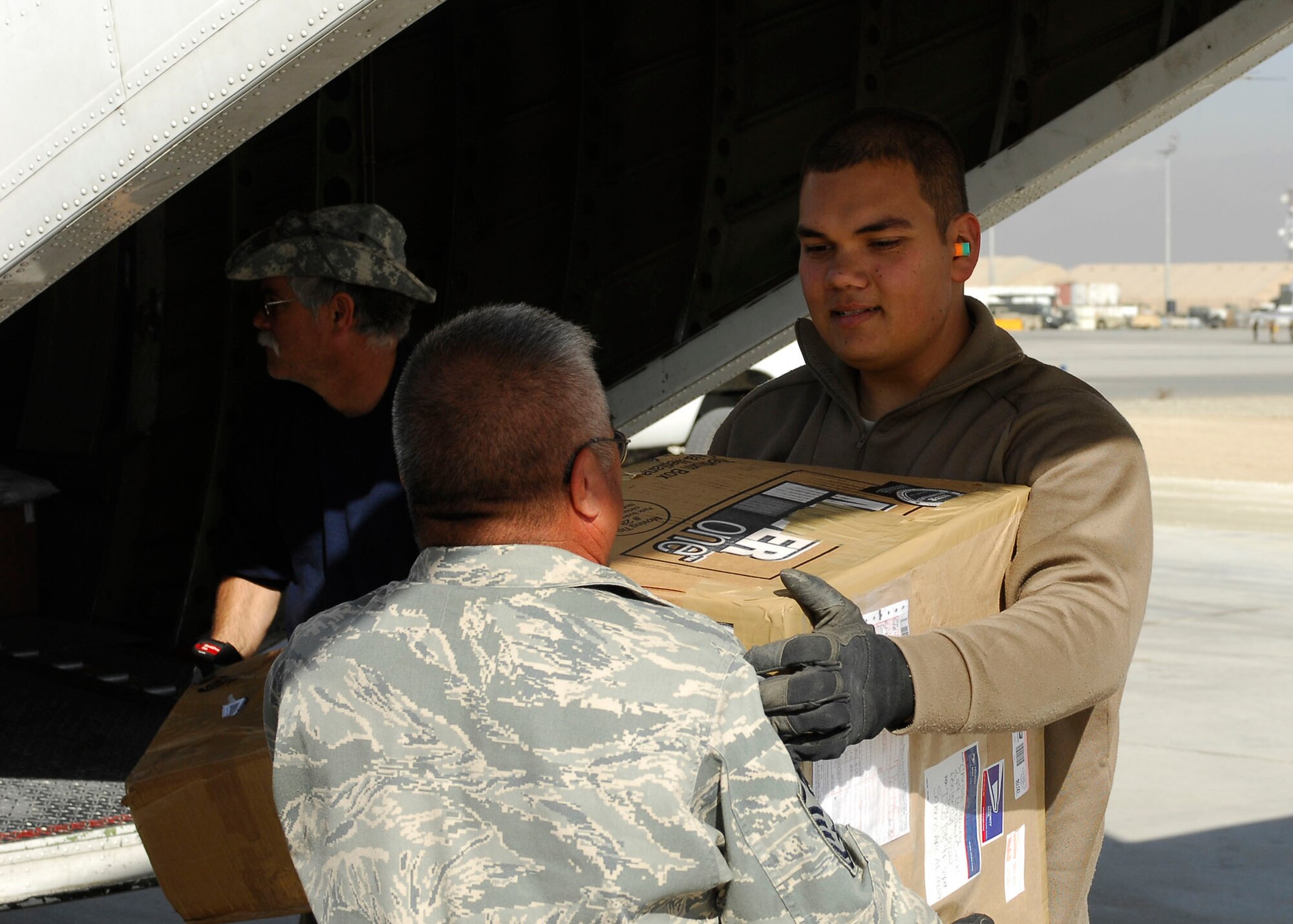 BAGRAM AIRFIELD, Afghanistan -- Master Sgt. Roque Fuentes (left) hands a box to Airman 1st Class Jericks Silver (right) as they load mail onto an aircraft Nov. 15, 2009.  Both of the Airmen are air transportation members from the short take off and landing office of the 455th Expeditionary Aerial Port Squadron.  The STOL office is in charge of delivering personnel and mail to different forward operating bases.   Airman Silver is deployed from Travis Air Force Base, Calif., and hails from Hamilton, Mo.  Sergeant Fuentes is deployed from Lackland AFB, Texas and hails from Corpus Christi, Texas.  (U.S. Air Force photo/Senior Airman Felicia Juenke)