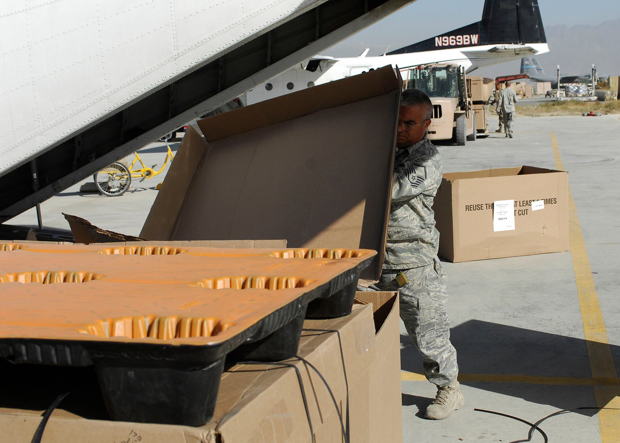 BAGRAM AIRFIELD, Afghanistan -- Master Sgt. Roque Fuentes, the non-commissioned officer in charge of the short take off and landing office of the 455th Expeditionary Aerial Port Squadron, gathers parts of the box used to hold mail Nov. 15, 2009.  The STOL office is in charge of delivering personnel and mail to different forward operating bases.   Sergeant Fuentes is deployed from Lackland Air Force Base, Texas and hails from Corpus Christi, Texas.  (U.S. Air Force photo/Senior Airman Felicia Juenke)