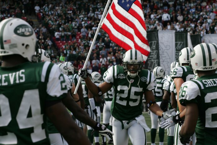 EAST RUTHERFORD, N.J. -- Kerry Rhodes #25, free safety, New York Jets, carrys an American Flag on field during pre-game introduction, Nov. 15. Marine Corps, Air Force, Navy, Coast Guard and Army service members participated in a tribute to veterans before the game. A Coast Guard detachment sang the National Anthem and were joined by a joint-service color guard before the New York Jets game against the Jacksonville Jaguars. Chief Master Sgt. James A. Roy, Chief Master Sergeant of the Air Force, presented the coin for the pre-game coin toss.(Official Marine Corps photo by Sgt. Randall A. Clinton)