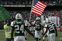EAST RUTHERFORD, N.J. -- Kerry Rhodes #25, free safety, New York Jets, carrys an American Flag on field during pre-game introduction, Nov. 15. Marine Corps, Air Force, Navy, Coast Guard and Army service members participated in a tribute to veterans before the game. A Coast Guard detachment sang the National Anthem and were joined by a joint-service color guard before the New York Jets game against the Jacksonville Jaguars. Chief Master Sgt. James A. Roy, Chief Master Sergeant of the Air Force, presented the coin for the pre-game coin toss.(Official Marine Corps photo by Sgt. Randall A. Clinton)