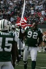 EAST RUTHERFORD, N.J. -- Shaun Ellis #92, defensive lineman, New York Jets, carrys an American Flag on field during pre-game introduction, Nov. 15. Marine Corps, Air Force, Navy, Coast Guard and Army service members participated in a tribute to veterans before the game. A Coast Guard detachment sang the National Anthem and were joined by a joint-service color guard before the New York Jets game against the Jacksonville Jaguars. Chief Master Sgt. James A. Roy, Chief Master Sergeant of the Air Force, presented the coin for the pre-game coin toss.(Official Marine Corps photo by Sgt. Randall A. Clinton)