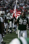 EAST RUTHERFORD, N.J. -- Shaun Ellis #92, defensive lineman, New York Jets, carrys an American Flag on field during pre-game introduction, Nov. 15. Marine Corps, Air Force, Navy, Coast Guard and Army service members participated in a tribute to veterans before the game. A Coast Guard detachment sang the National Anthem and were joined by a joint-service color guard before the New York Jets game against the Jacksonville Jaguars. Chief Master Sgt. James A. Roy, Chief Master Sergeant of the Air Force, presented the coin for the pre-game coin toss.(Official Marine Corps photo by Sgt. Randall A. Clinton)