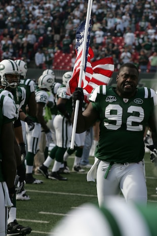 EAST RUTHERFORD, N.J. -- Shaun Ellis #92, defensive lineman, New York Jets, carrys an American Flag on field during pre-game introduction, Nov. 15. Marine Corps, Air Force, Navy, Coast Guard and Army service members participated in a tribute to veterans before the game. A Coast Guard detachment sang the National Anthem and were joined by a joint-service color guard before the New York Jets game against the Jacksonville Jaguars. Chief Master Sgt. James A. Roy, Chief Master Sergeant of the Air Force, presented the coin for the pre-game coin toss.(Official Marine Corps photo by Sgt. Randall A. Clinton)