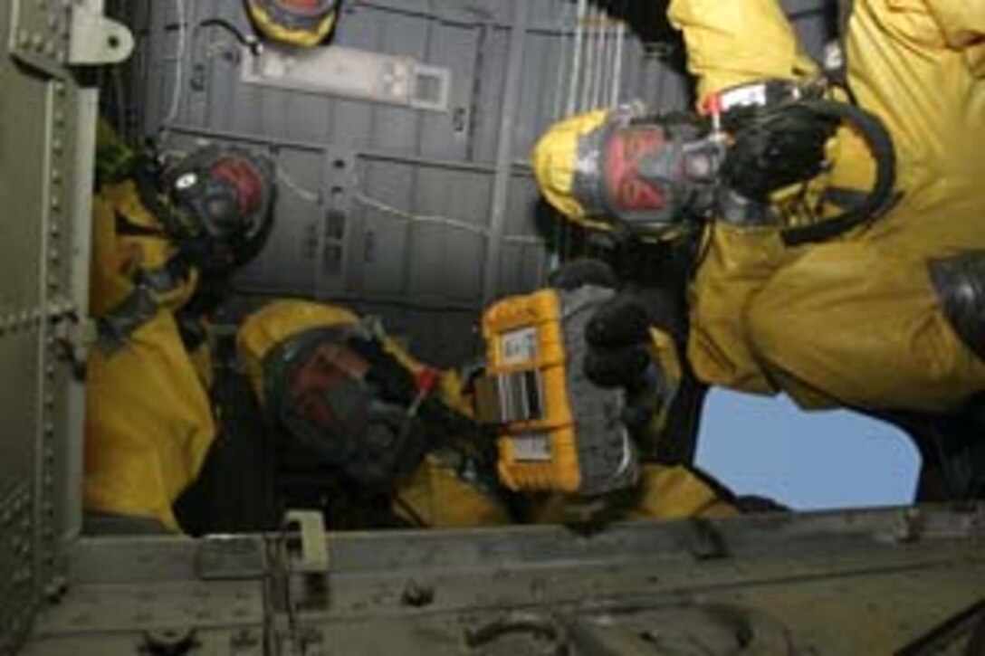 MARINE CORPS BASE CAMP PENDLETON, Calif.?Members of the 11th Marine Expeditionary Unit?s Enhanced Chemical, Biological, Radiological and Nuclear Defense Team peer through the ?hell-hole? of a CH-46E Sea Knight helicopter while looking for possible toxic agents onboard June 21, here. Marines and sailors from Battery G, Battalion Landing Team 1st Battalion, 5th Marine Regiment, 11th Marine Expeditionary Unit, from here, took part in a three-week training exercise to provide the 11th MEU with a confined space, site exploitation capability to respond to a CBRN incident.