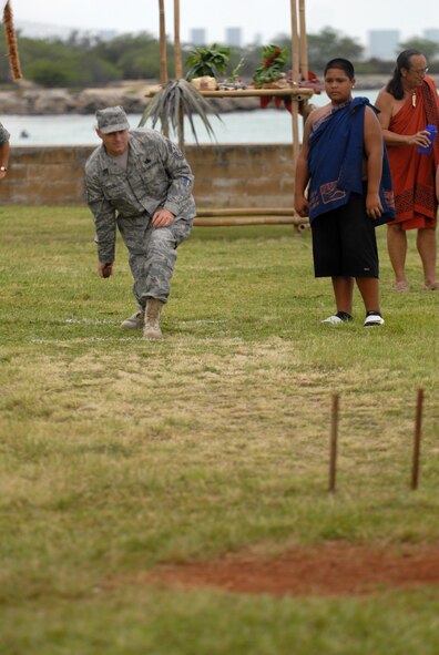 HICKAM AIR FORCE BASE, Hawaii -- Chief Master Sgt. Craig Recker, 15th Airlift Wing command chief, attempts to roll a rock through two sticks as part of a game during the Makahiki Festival here, Nov. 14. For more than two-thousand years, the significance of Lono and his contributions to the beliefs and practices of the early Hawaiian people, influenced the celebration of events held during the Makahiki Festival throughout the Hawaiian Islands. Since Lono was the embodiment of all the characteristics of peace and welfare, all warfare was strictly forbidden during the time of the Makahiki. Since Lono represented the spiritual life-force that came out of all agricultural efforts, much feasting of every kind was done during the four months of the Makahiki. This focus on health and welfare made games of skill that tested a healthy body and mind a focal point of the Makahiki games. (U.S. Air Force photo/Senior Airman Gustavo Gonzalez)