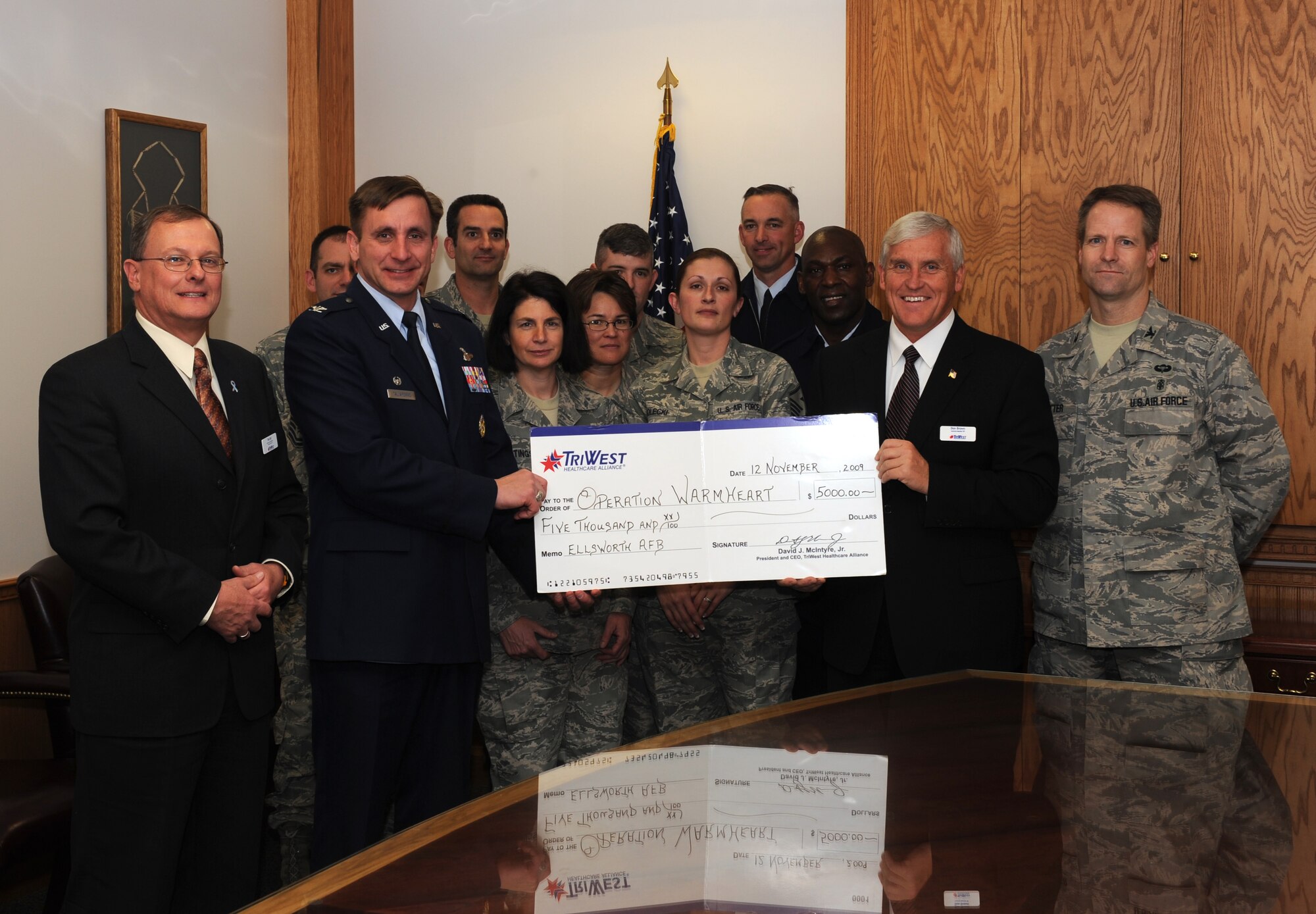 ELLSWORTH AFB, S.D. -- (Center left) Col. Jeffrey Taliaferro, 28th Bomb Wing commander accepts a check from (center right) Mr. Donald Brown, TRIWEST Healthcare Alliance, for Operation Warmheart Nov 12. Operation Warmheart is a year-round program managed by the First Sergeants Council and is supported by volunteers. It is designed to assist Airmen and their families with financial issues. (U.S. Air Force photo/Master Sgt. Loren J. Bonser)