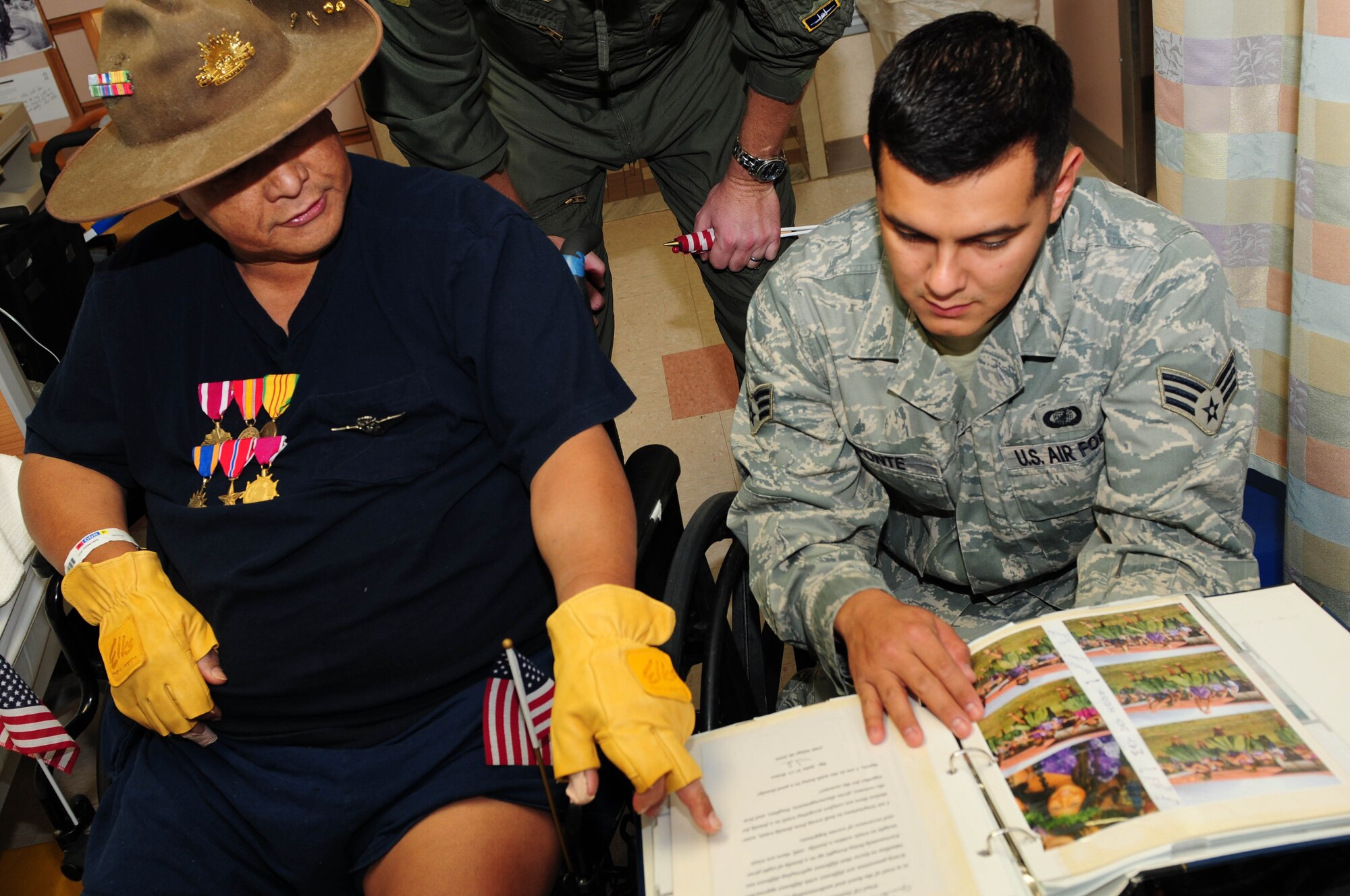 A veteran from Tripler Army Medical Center's Community Living Center in Honolulu, Hawaii shows Senior Airman Andres Aponte, a finance technician from the 15th Comptoller Squadron at Hickam Air Force Base, Hawaii, his family photo album during a visit by the Hickam Green Knights Motorcycle club on Veterans Day, Nov. 11. The group spent time handing out commemorative U.S. flags that reflect the spirit of Veterans Day. The bikers also helped the veterans move about the center and took them outside for a quick view of their bikes which filled a large portion of the parking lot. (Air Force photo/ Tech. Sgt. Kerry Jackson)