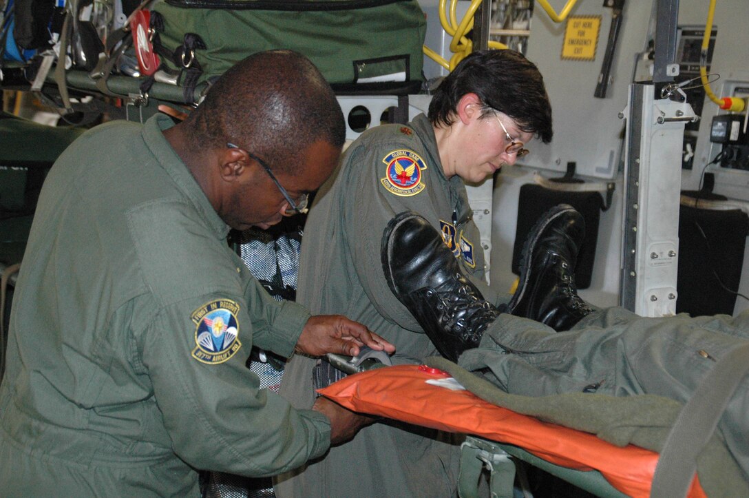 Master Sgt. Reggie Godbolt (left), a loadmaster with the 317th Airlift Squadron, Charleston AFB, S.C., helps Maj. Michelle Rowe, flight nurse with the 439th Aeromedical Evacuation Squadron, Westover ARB, Mass., secure a simulated patient on a joint C-17 training mission.  (Air Force photo/Capt. Wayne Capps)
