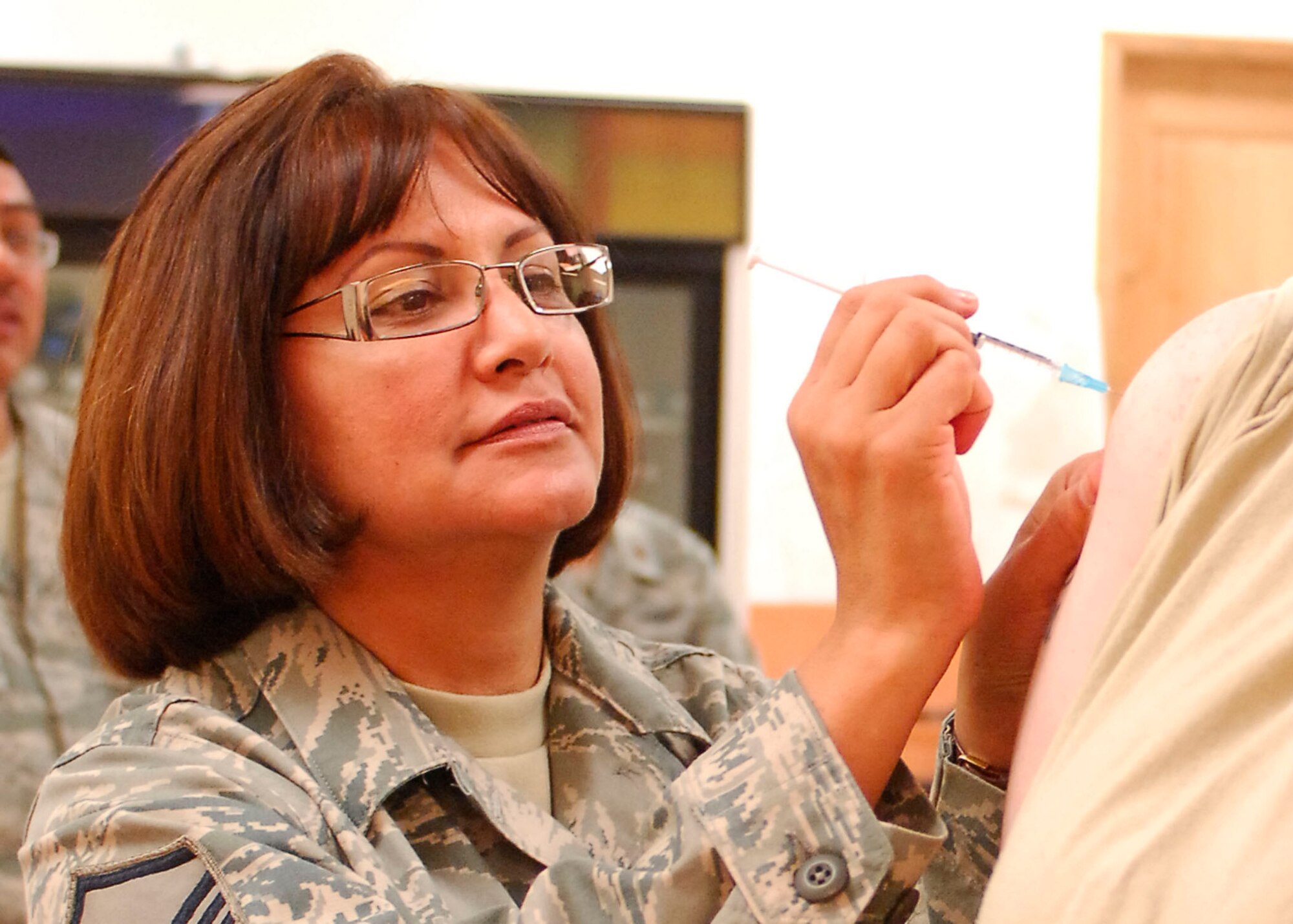 BAGRAM AIRFIELD, Afghanistan -- Senior Airman Felicia Juenke (right), a photographer from the 455th Air Expeditionary Wing , receives the Influenza A 2009 (H1N1) Monovalent vaccine from Master Sgt. Maria Langston (left), the emergency room non-commissioned officer in charge from the 455th Expeditionary Medical Operation Squadron, Nov. 16, 2009.  Airman Juenke is deployed from Dyess Air Force Base, Texas and hails from Victoria, Texas.  Sergeant Langston, a San Antonio native, is deployed from Lackland AFB, Texas.  (U.S. Air Force photo/Senior Airman Susan Tracy)