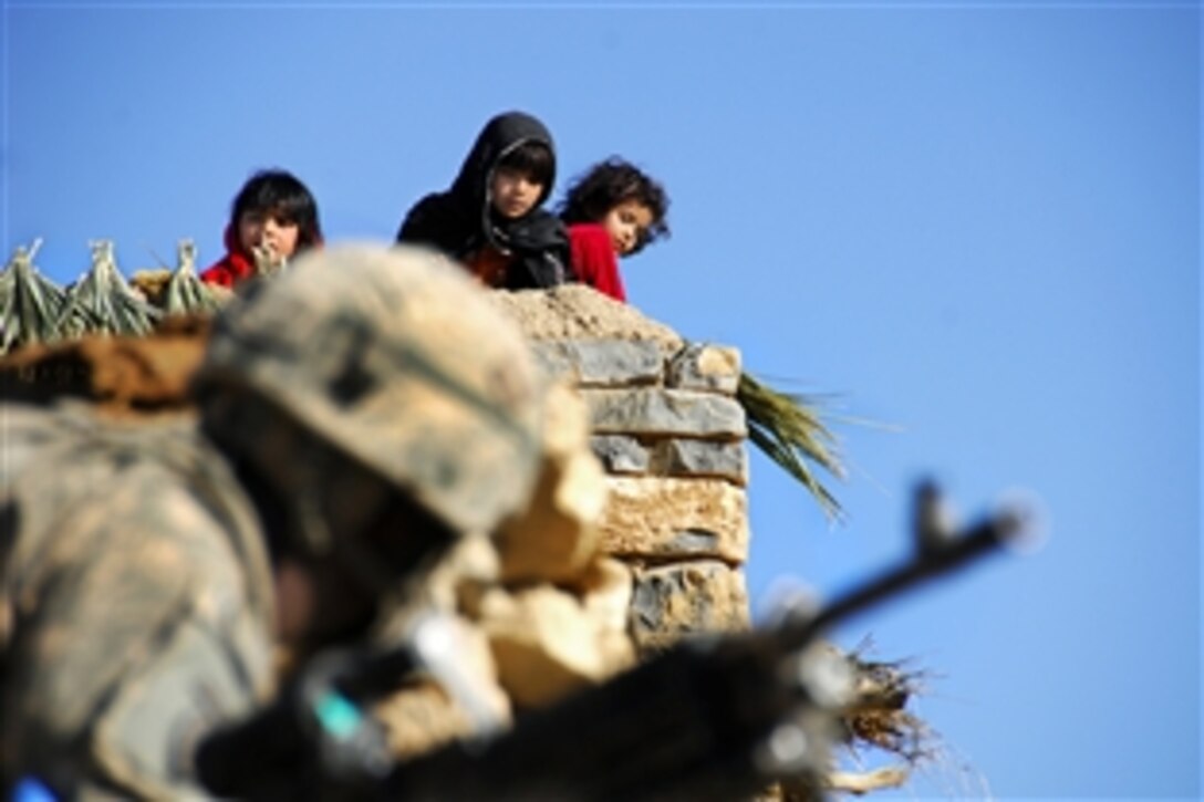 Afghan children on a rooftop watch a U.S. Army soldier below as he performs perimeter security during a mission in the village of Miricalai, Khowst province, Afghanistan, Nov. 11, 2009. The soldiers are assigned to the 25th Infantry Division's Company D, 1st Battalion, 501st Regiment, 4th Brigade.