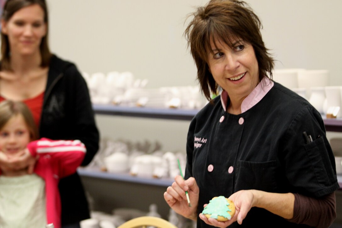 Rosanne Zinniger, workshop instructor and owner of Ro Z’s Sweet Art Studio in San Marcos, Calif., smiles while showing class participants the different cookie icings at Camp Pendleton’s Hobby Shop, Nov. 17.