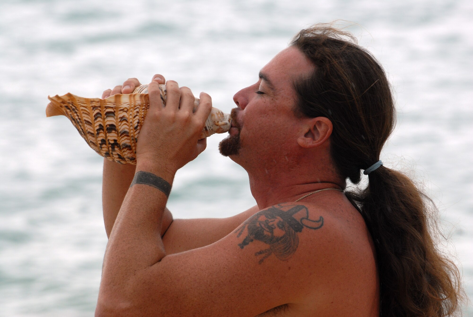 HICKAM AIR FORCE BASE, Hawaii - Mark Naone, blows into a chonch shell also refered to as a Pu, announcing the arrival of Lono in the native Hawaiian language during the opening ceremonies for the 7th Annual Kapuaikaula (Hickam) Makahiki (Thanksgiving) festival. Local Hawaiian and Hickam officials gathered at Hickam Harbor on Nov. 14 for the Makahiki festival. The festival involved a ceremonial arrival in canoes, spiritual offerings, five skills competitions and a feast to end the day. According to history texts, the Makahiki was started to honor Lono, the Hawaiian guardian of agriculture, rain, health and peace. (U.S. Air Force photo/Senior Airman Gustavo Gonzalez)