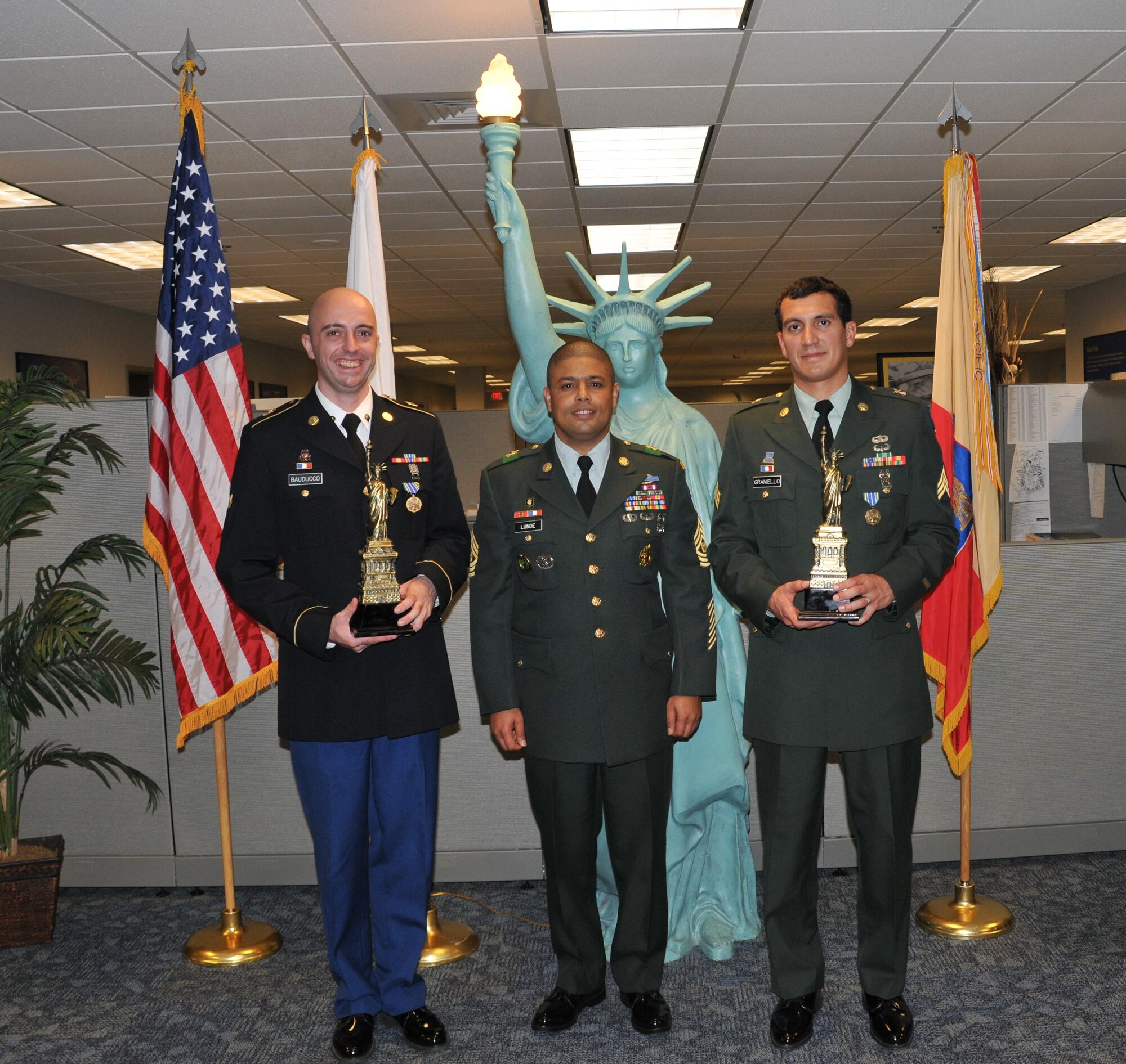 Sgt. John Graniello, Command Sgt. Maj. Najee Lunde and Spc. Paul Bauducco display models of the Statue of Liberty at the headquarters of the 77th Sustainment Brigade. Sergeant Graniello and Specialist Bauducco, as winners of the Best Warrior Competition, were awarded the Army Achievement Medal. They will go on to compete in the 316th Expeditionary Sustainment Command  BWC. (U.S. Air Force courtesy photo).