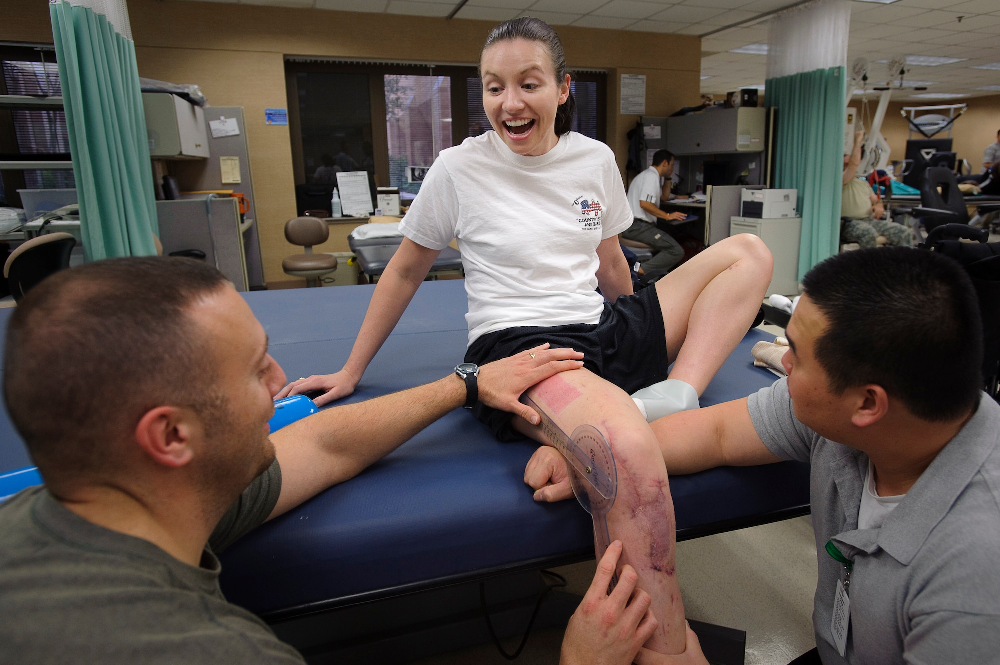 Capt. Wendy Kosek, 19th Airlift Wing legal officer from Little Rock Air Force Base, Ark., reacts to her latest range of motion test conducted by John Inzinna, left, and Anhtuan Pham, during physical therapy Brooke Army Medical Center. When she started physical therapy Kosek had just 30 degrees of mobility in her knee. She is currently up to 63 degrees and her goal is a 10 degree increase per week. (U.S. Air Force photo/Steve Thurow)