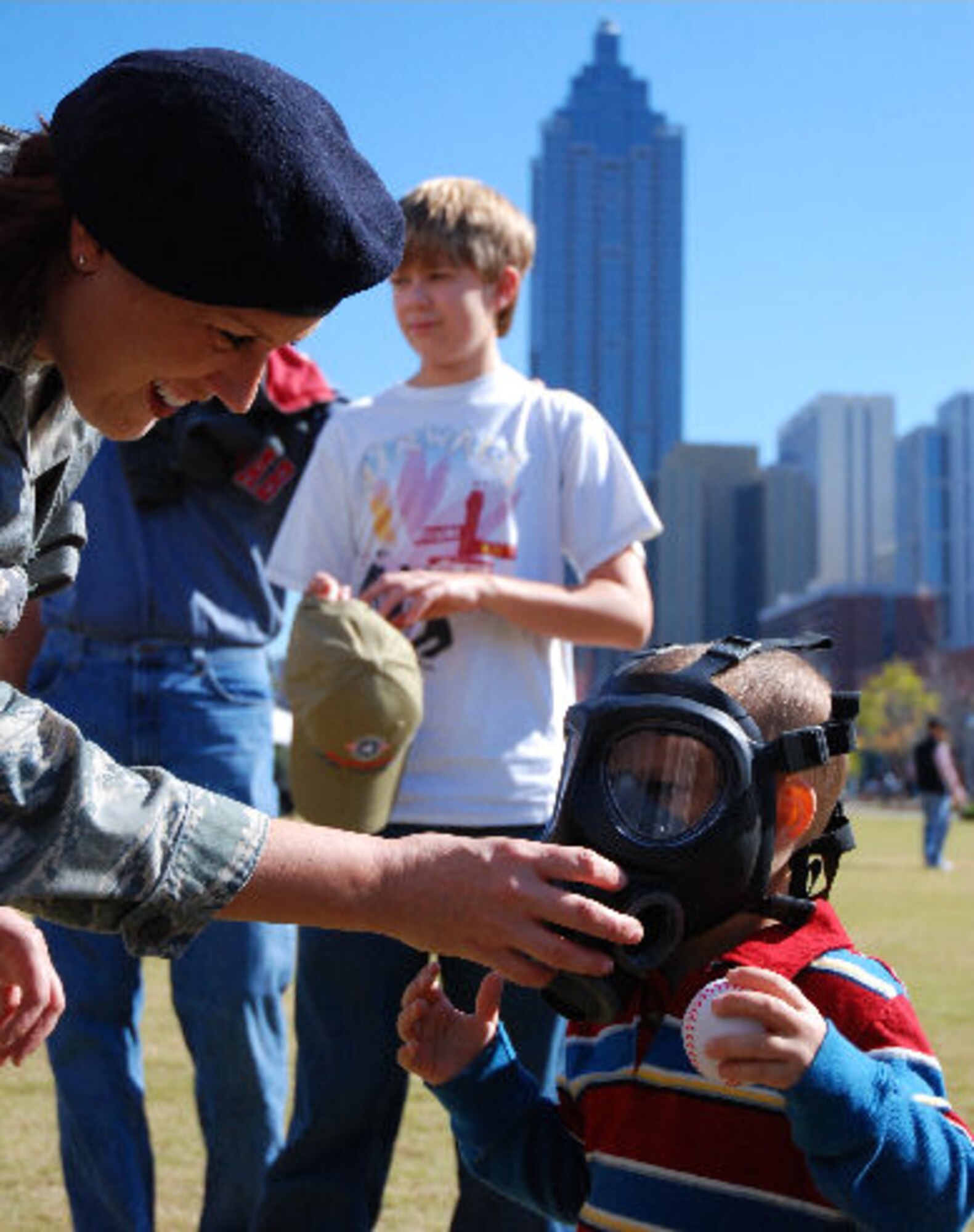 Staff Sgt. Amy Mahar, a 94th Security Forces Squadron member, places a gas mask on an eager Tucker Meyer, son of Air Force member Airman 1st Class John Meyer.
Sergeant Mahar and other members of the 94th SFS set up and manned a display of equipment in support of Military Appreciation Day, an event held Nov. 7, that included aerial demonstrations, static displays, and other military support organizations in downtown Atlanta at the World of Coca Cola location.  (U.S. Air Force photo/Airman Chelsea Gitzen)


