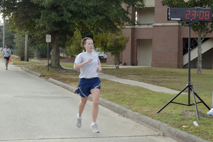 Lisa McCranie crosses the finish line  during the Run the Runway 5K event honoring retired Brig. Gen. Thomas Mikolajcik here on Wingman Day Nov. 17. The first place female finisher was recognized with a trophy at the event and her name will be placed on another trophy, which will be on display at the Child Development Center. McCranie assigned to the 15th Airlift Squadron and finished the 5K in 23:08. (U.S. Air Force photo/Staff Sgt. Marie Brown)